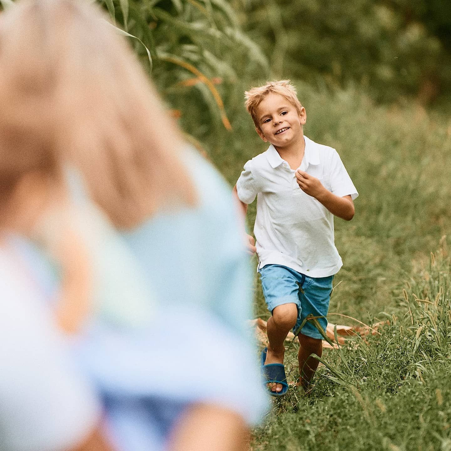 A child runs playfully through green grass on a sunny summer day.