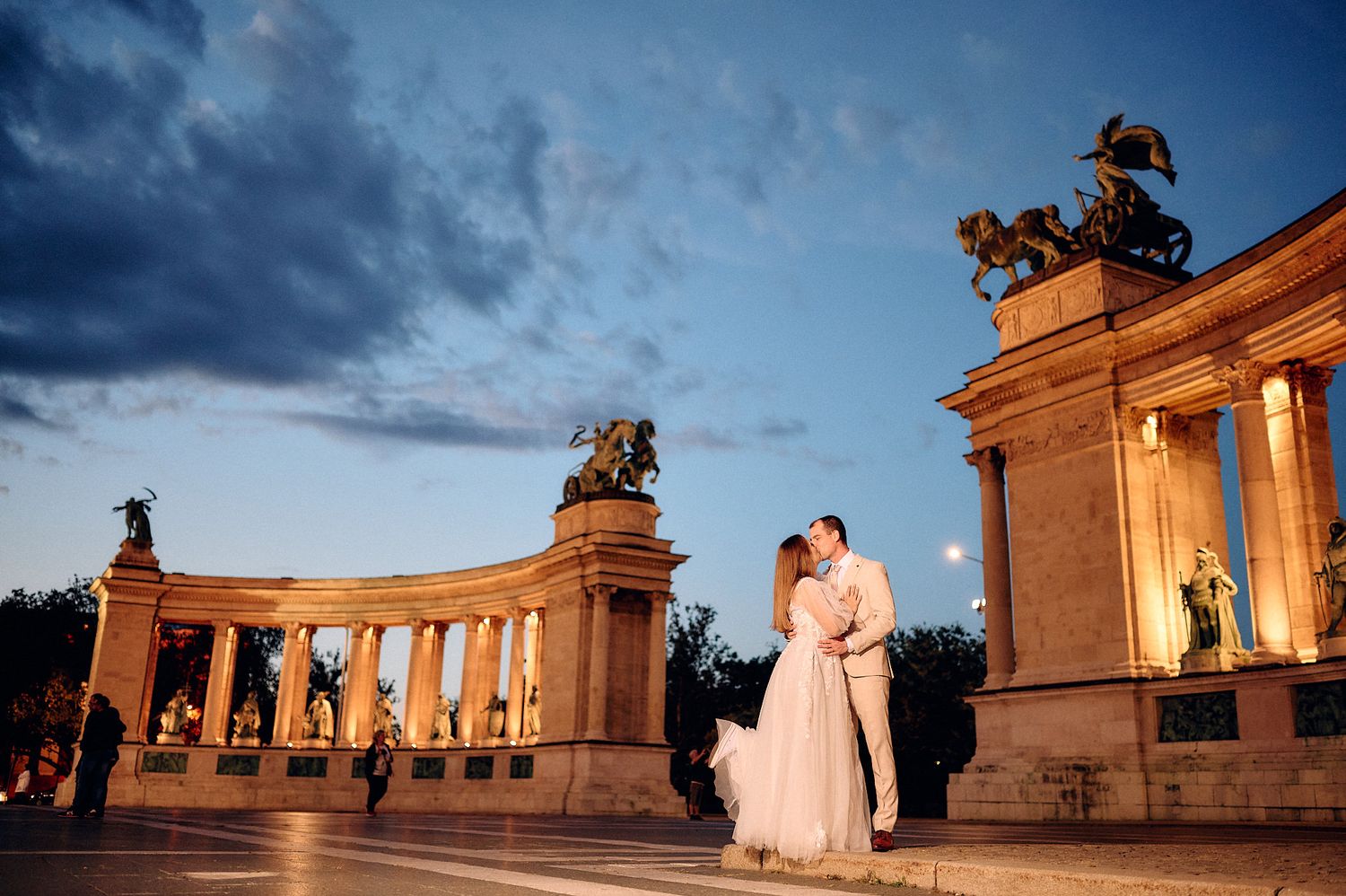 Elegant wedding portrait at Heroes Square monument during sunset in Budapest.