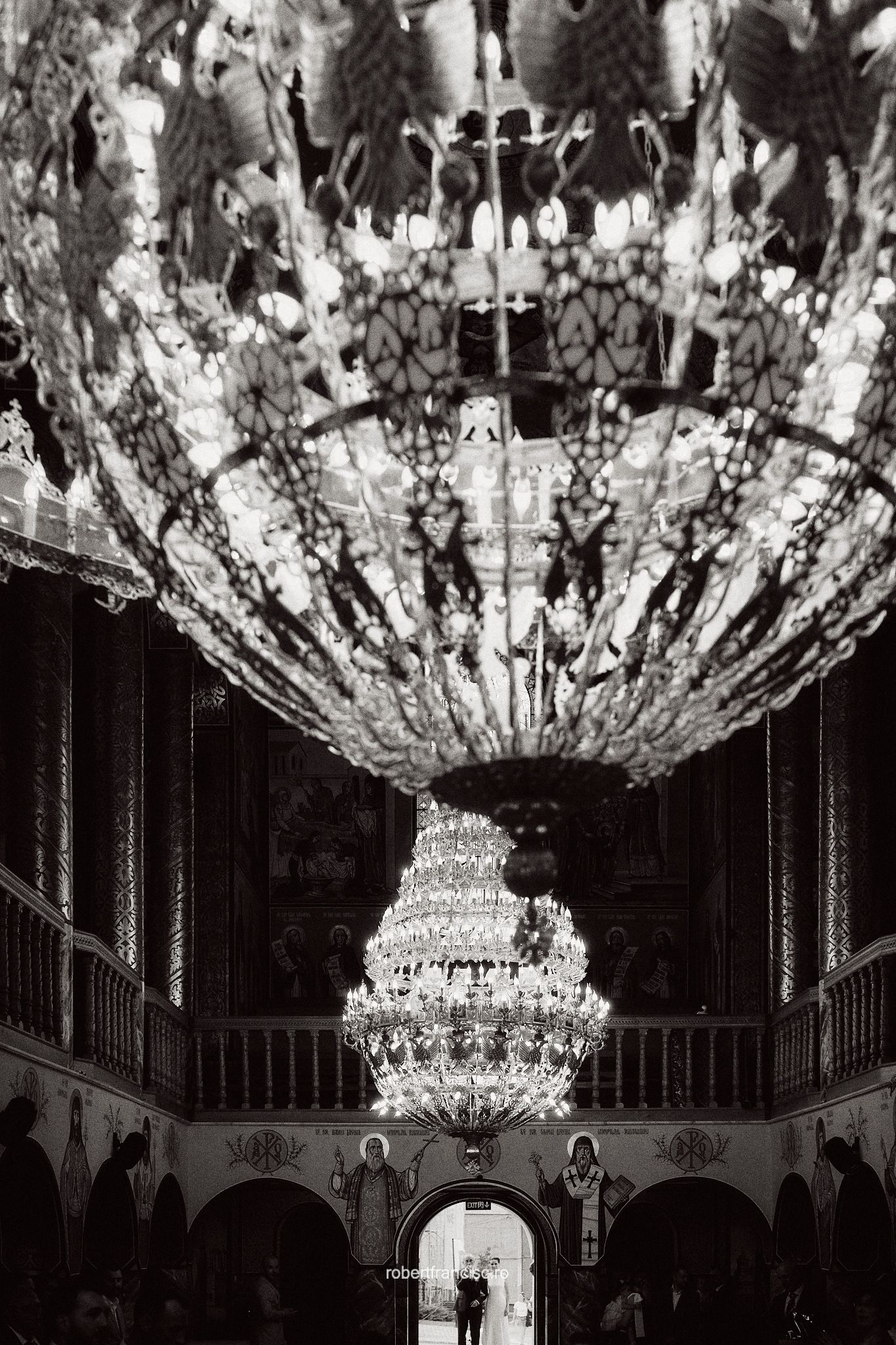 An ornate crystal chandelier with intricate details hangs majestically in a grand ballroom.