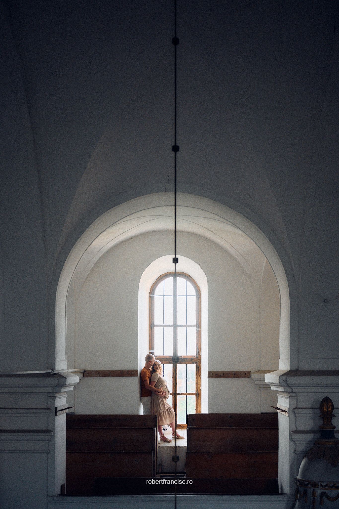 Elegant arched archways and white walls frame a lone figure in a flowing dress standing against a large glass door.
