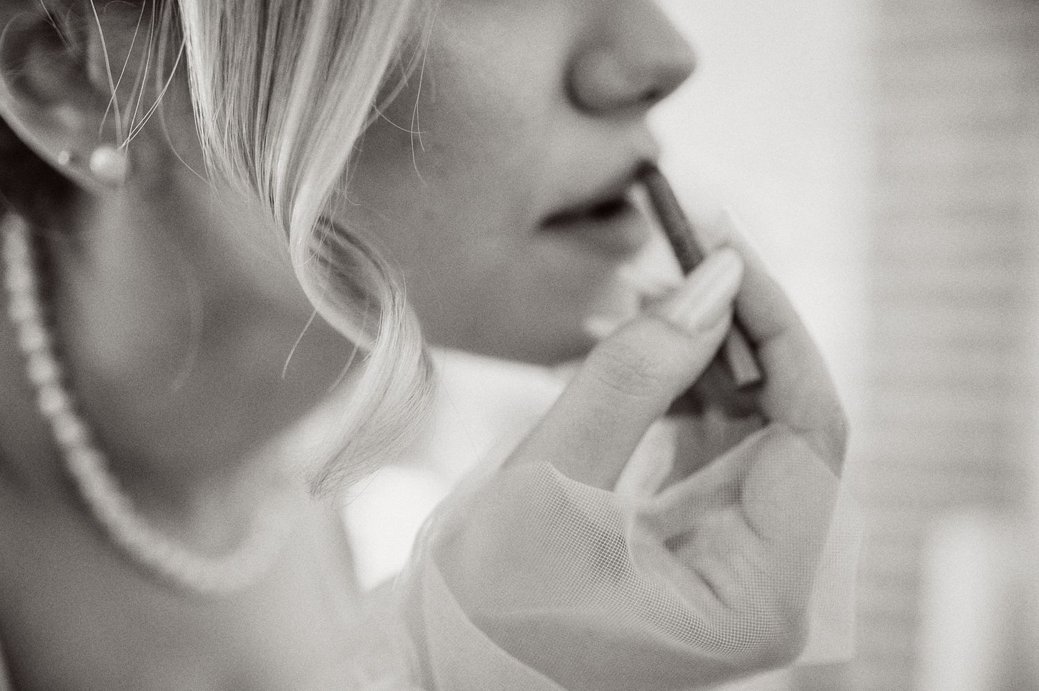 Close-up profile shot showing pearl necklace and elegant bridal makeup application.