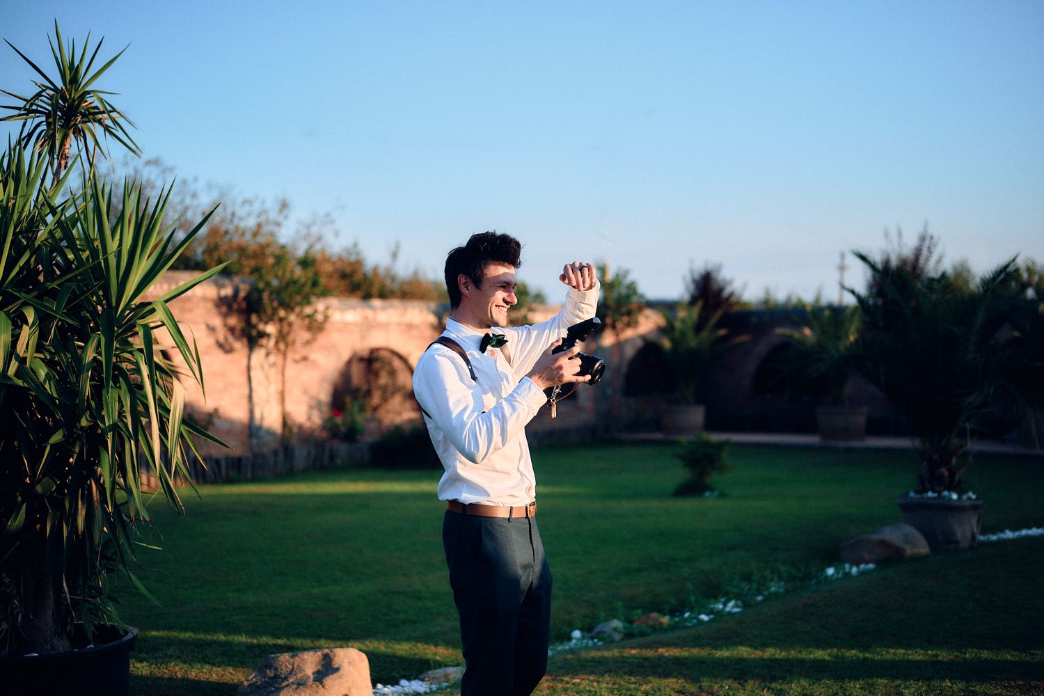 Wedding photographer taking photos outdoors against scenic natural backdrop.