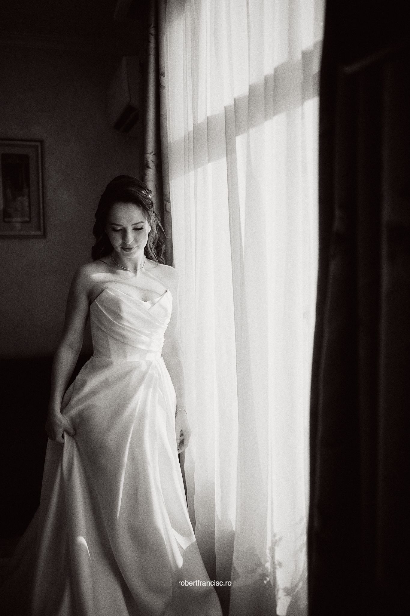 A series of black and white photos showing a figure in flowing white fabric standing by sunlit windows.