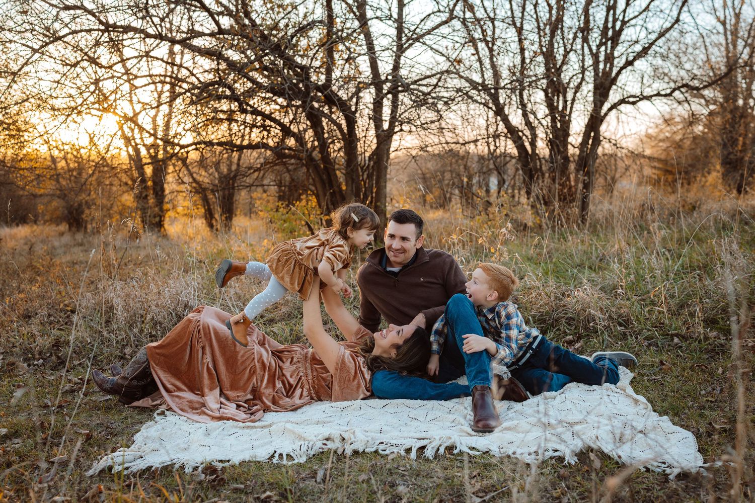 Family sits in the golden light in a Des Moines area park at sunset during a lifestyle family photo session.