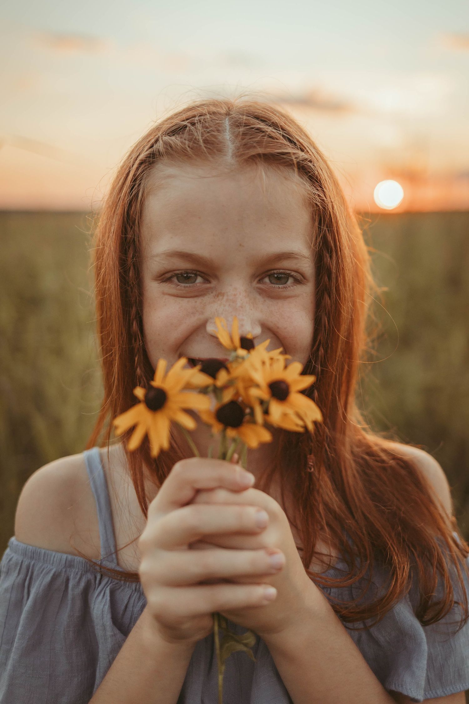 Young girl hold flowers to her face in a Des Moines area park during a lifestyle child milestone session.
