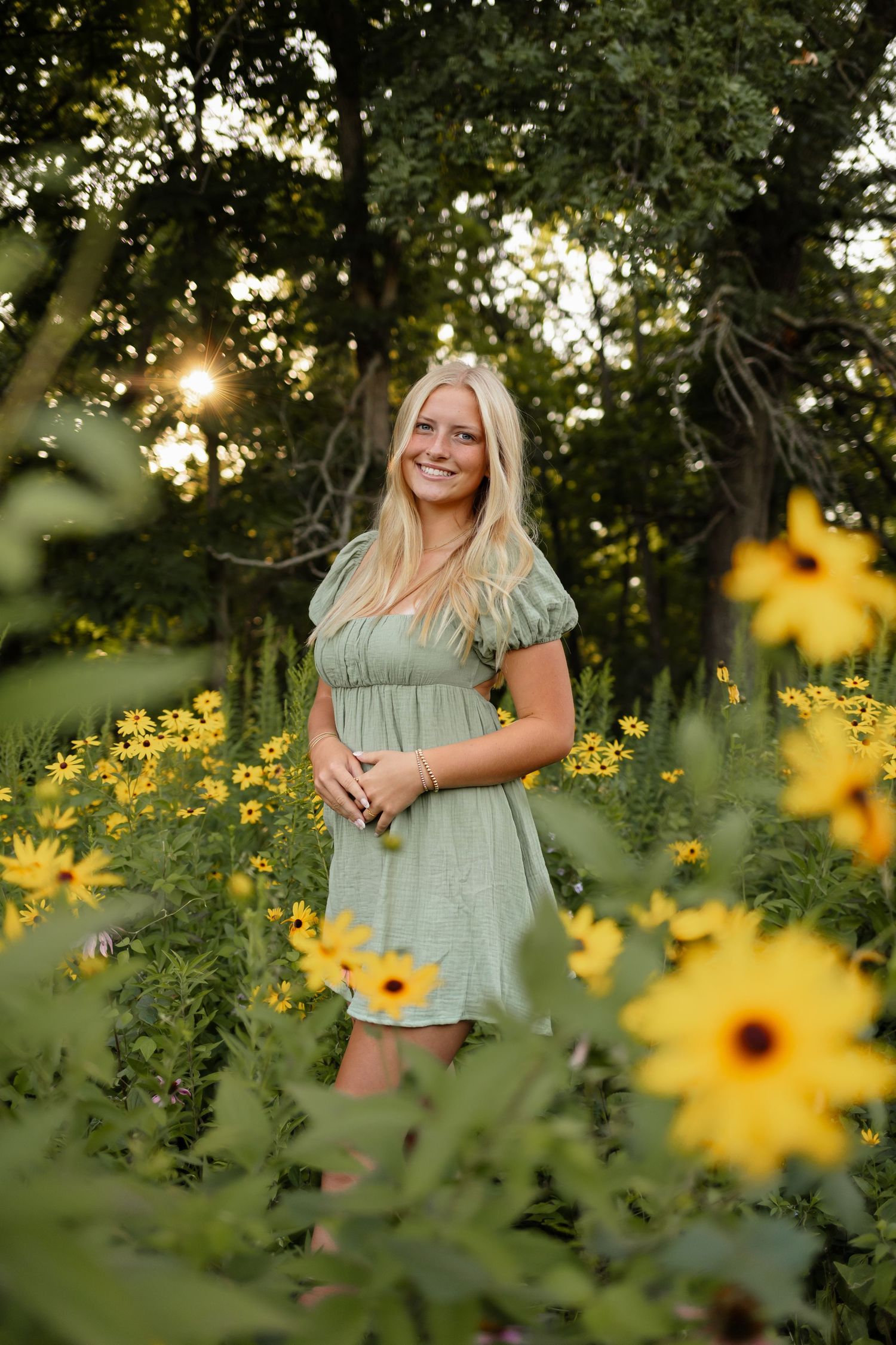 High school senior girl poses in a field of flowers in a Des Moines area park during a lifestyle senior photo session.