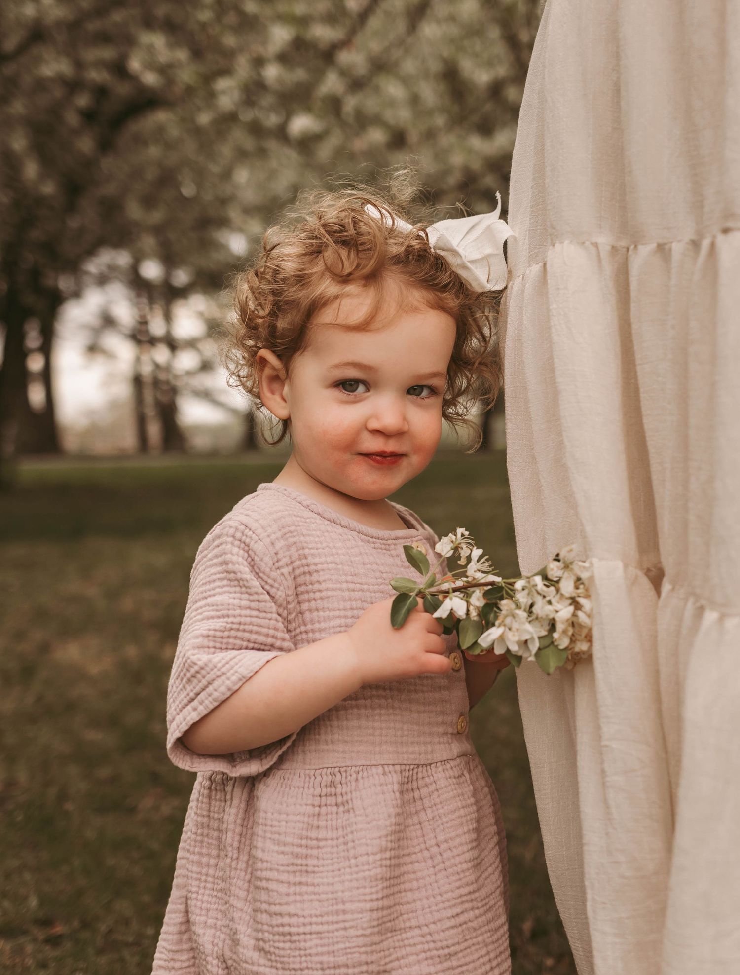 Young girl holds flowers in a Des Moines area park during a lifestyle family child milestone photo session.