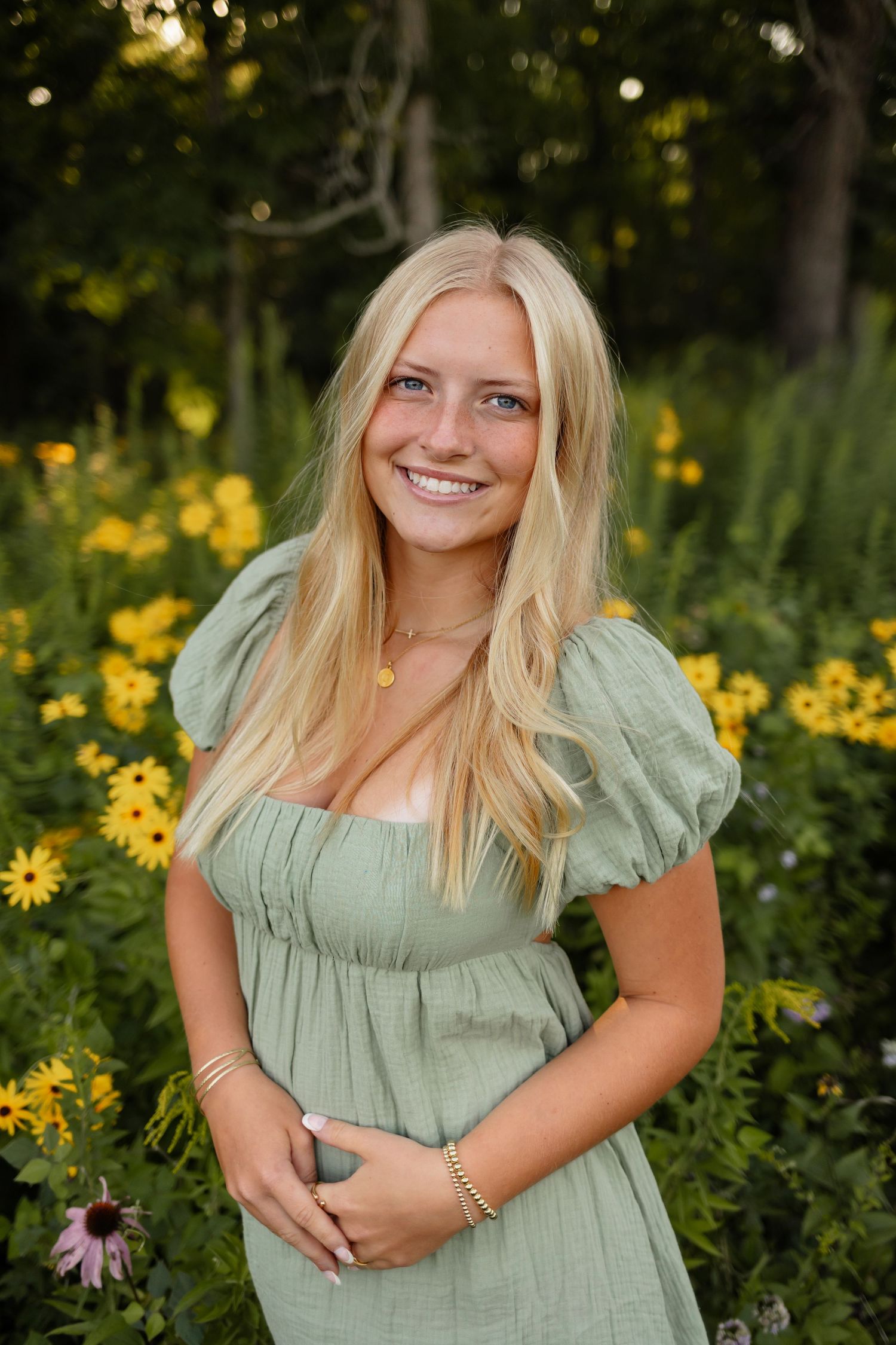 High school senior girl poses in a field of flowers in a Des Moines area park during a lifestyle senior photo session.