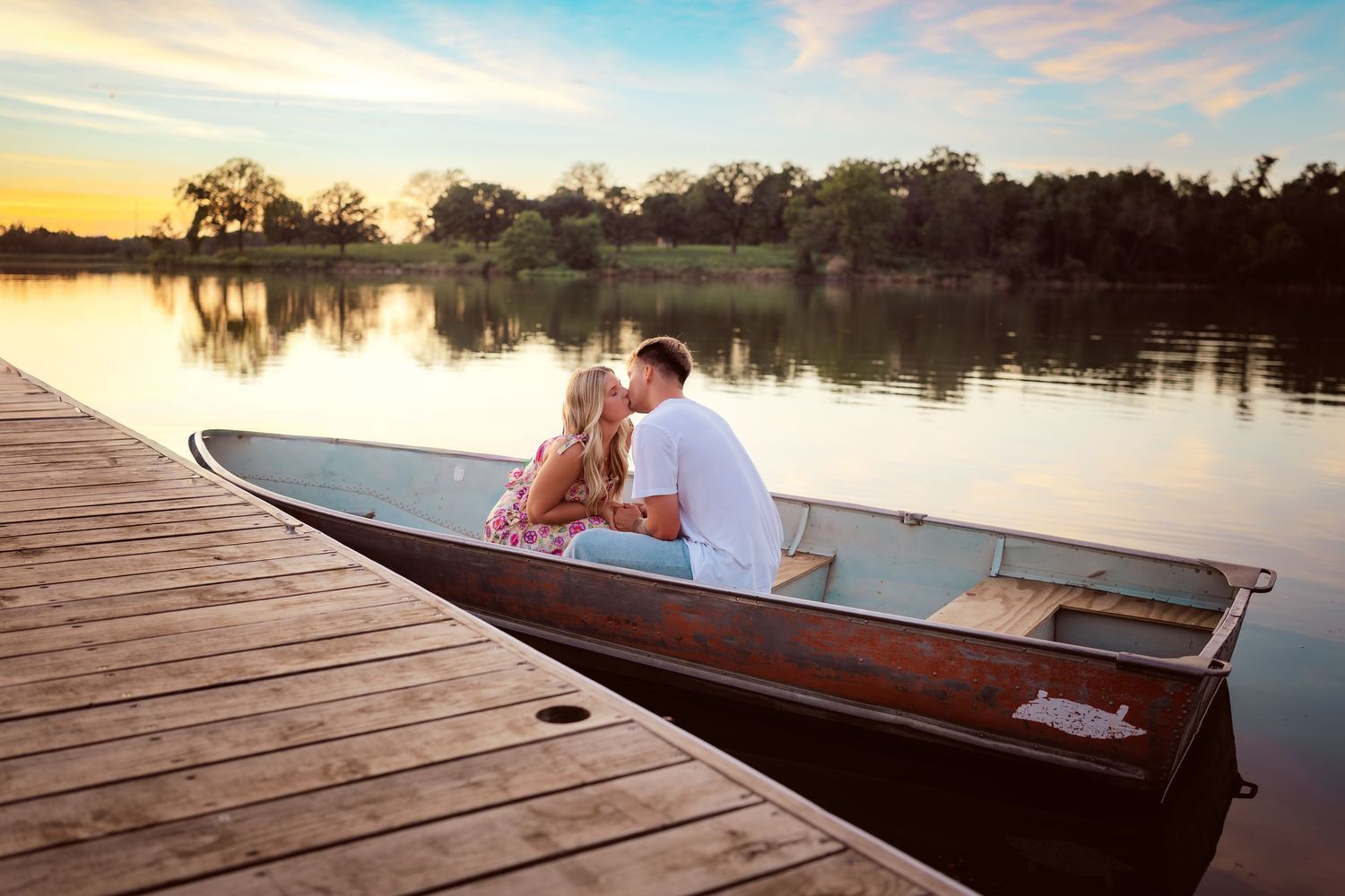 Couple kisses in boat in a Des Moines area park at sunset during a lifestyle family photo session.