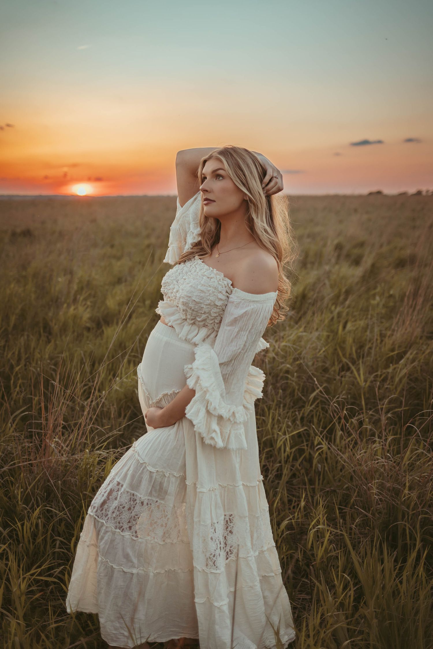 Pregnant woman in a Des Moines area field at sunset during lifestyle maternity photo session.