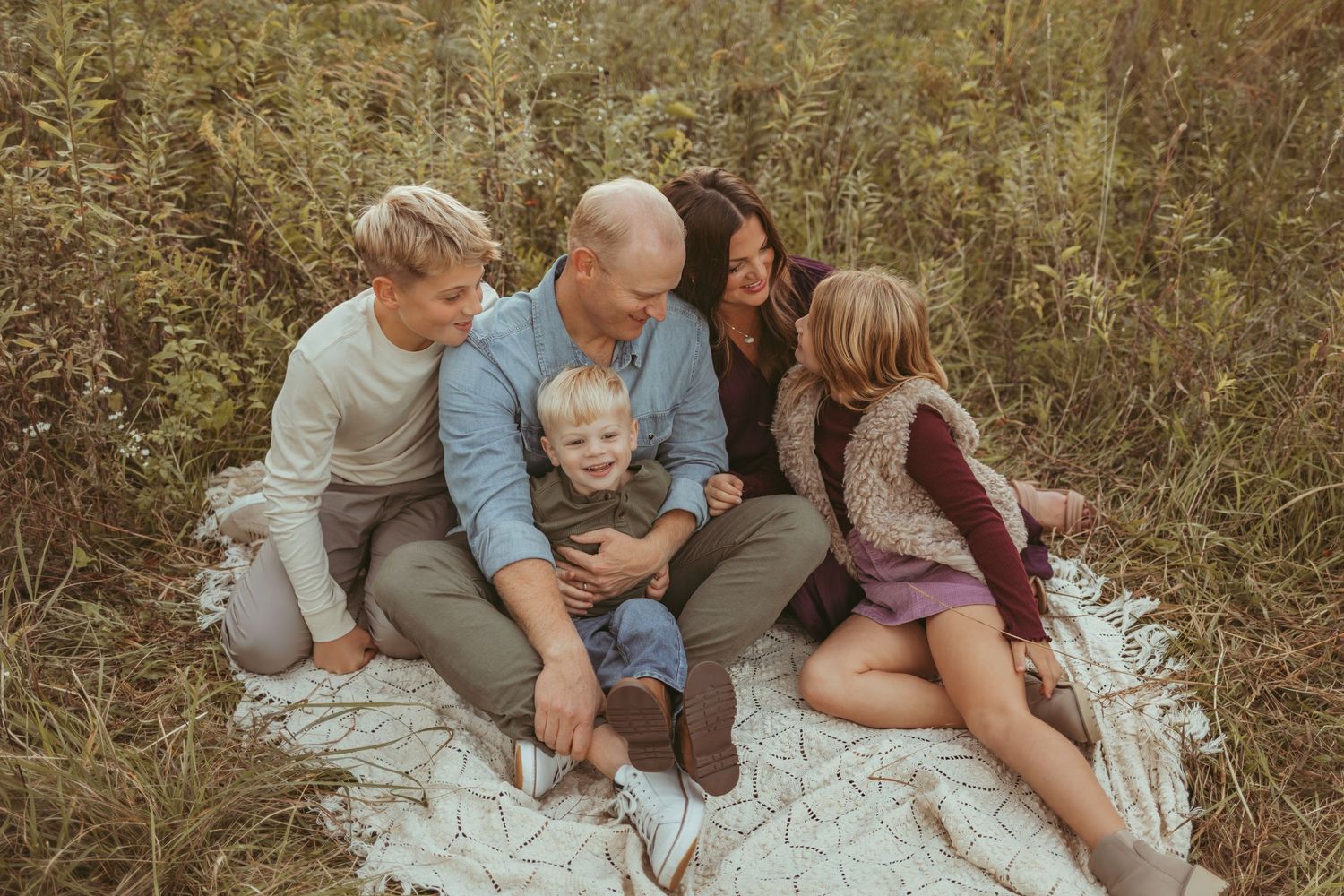 Family sits together on a vintage blanket in a Des Moines area park during a lifestyle family session.