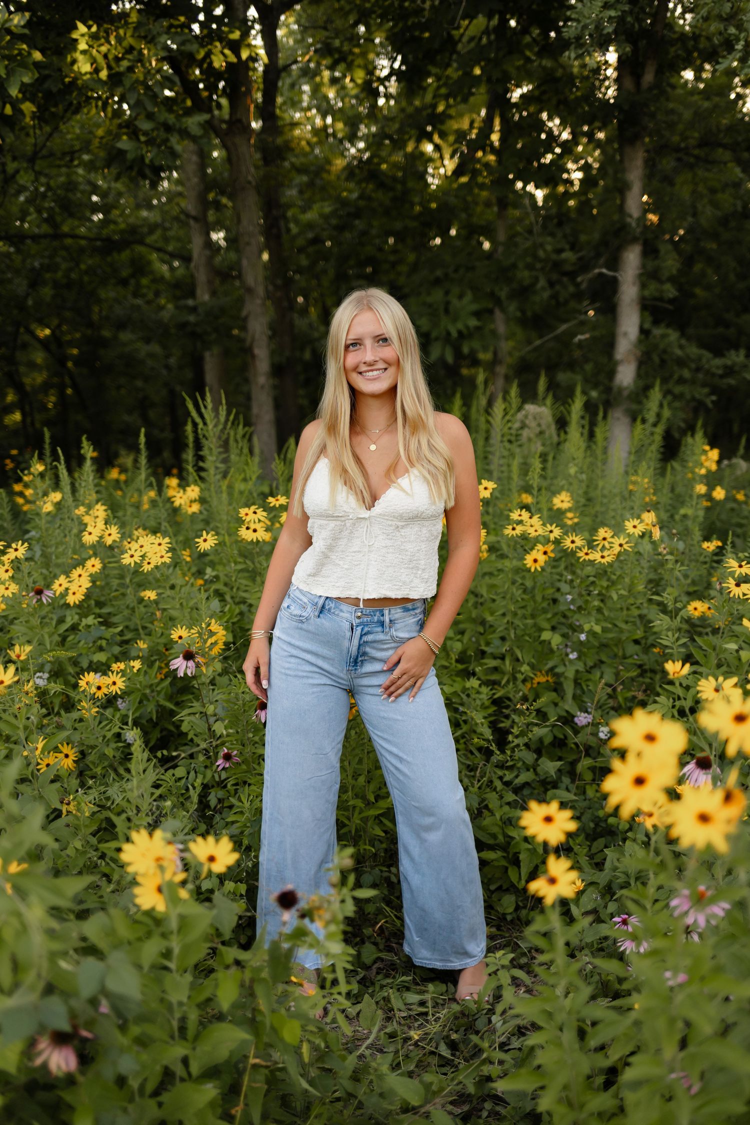 High school senior girl poses in a field of flowers in a Des Moines area park during a lifestyle senior photo session.
