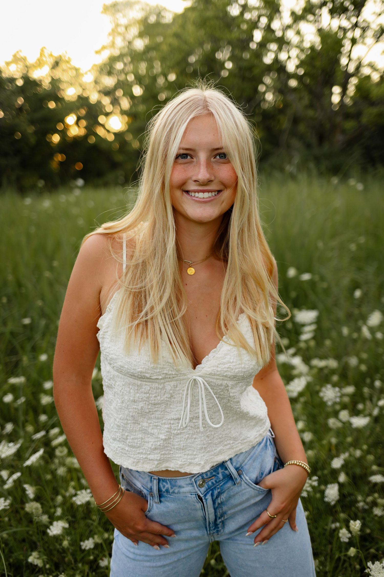 High school senior girl poses in a field of flowers in a Des Moines area park during a lifestyle senior photo session.