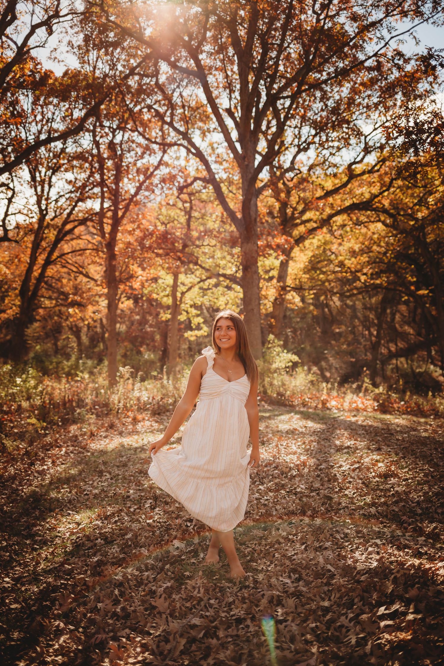 High school senior girl poses in a Des Moines area park in the fall during a lifestyle senior photo session.