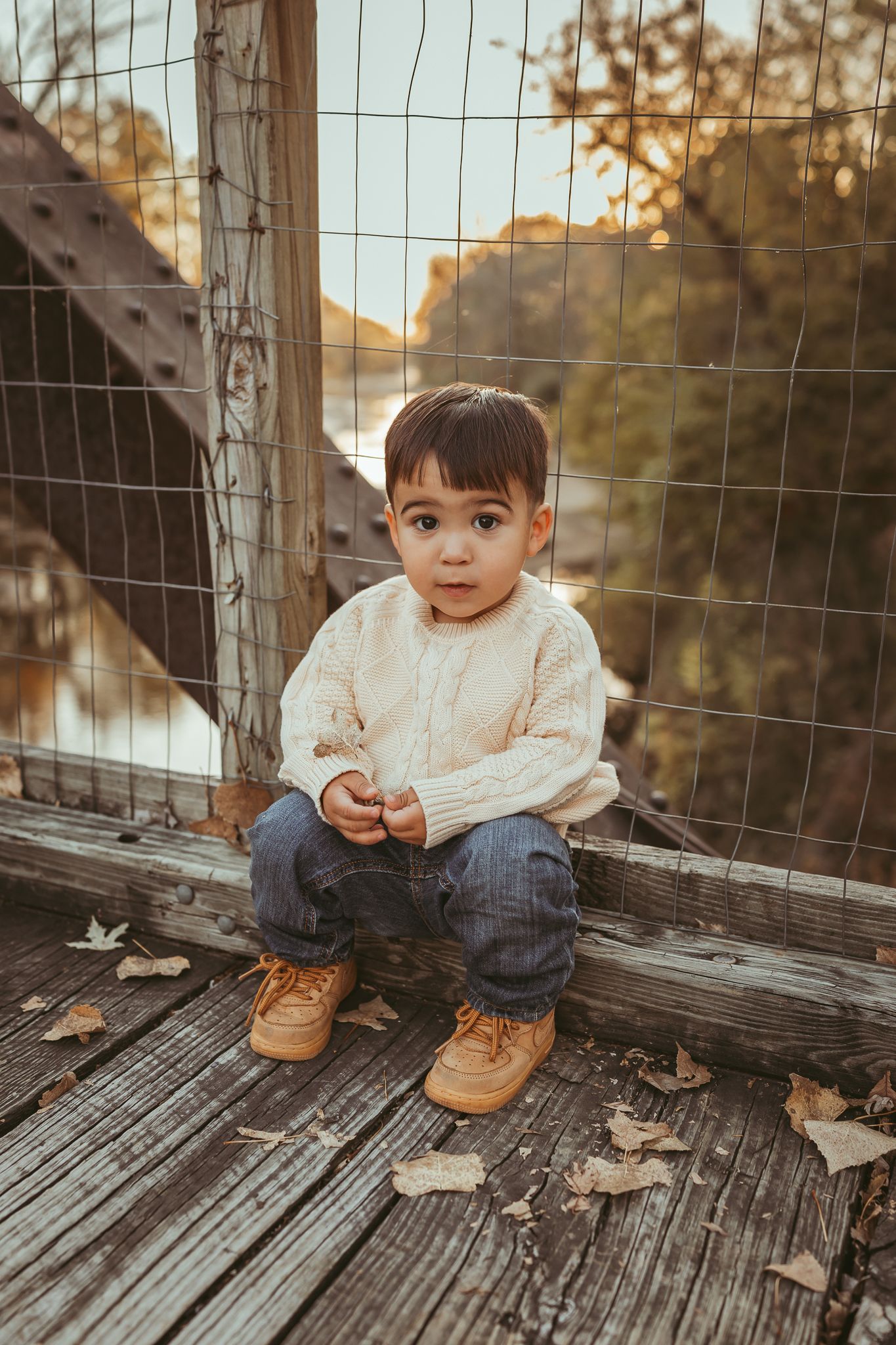 Young boy sits on bridge in a Des Moines area park during a lifestyle family child milestone photo session.