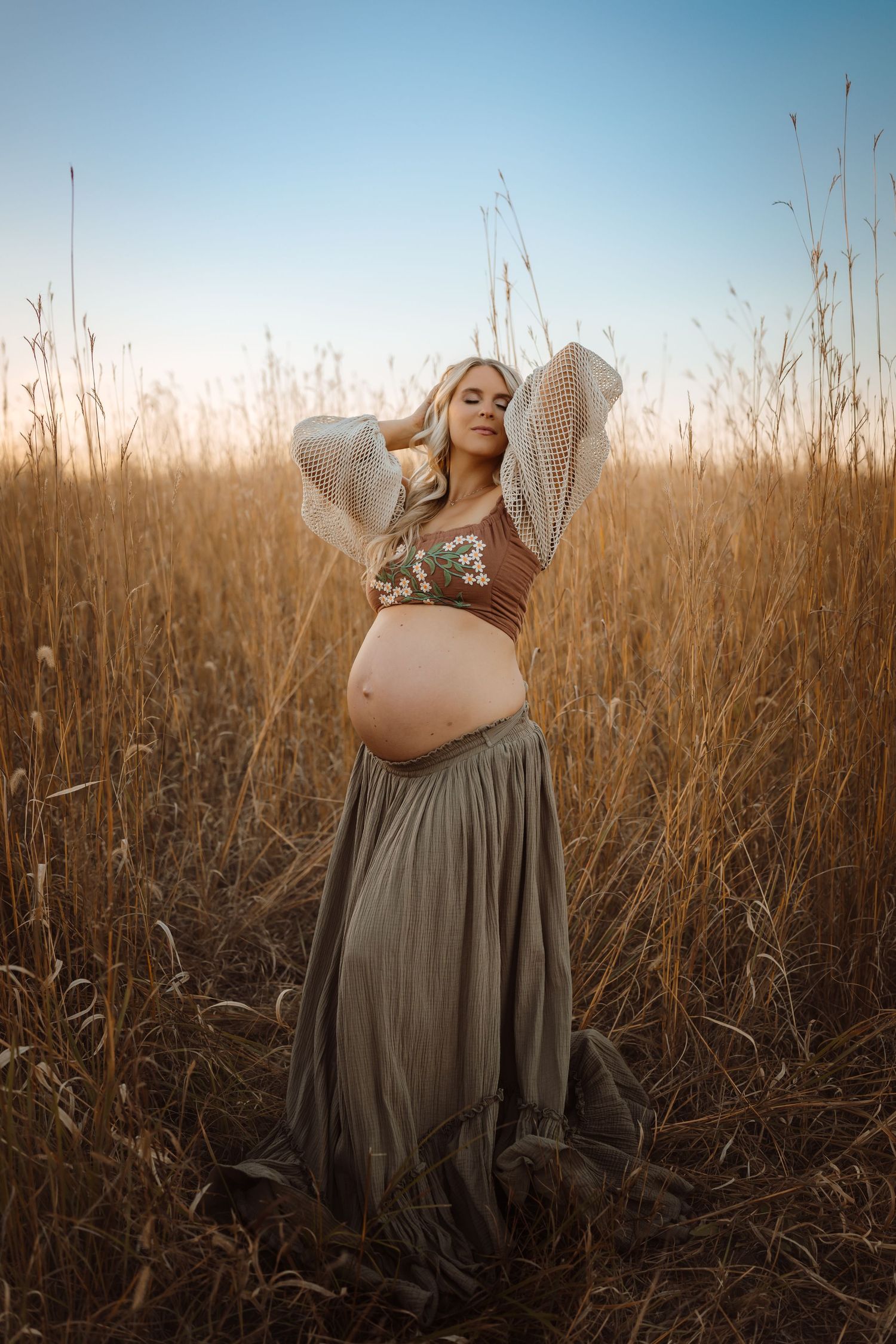 Pregnant woman in a Des Moines area field at sunset during lifestyle maternity photo session.