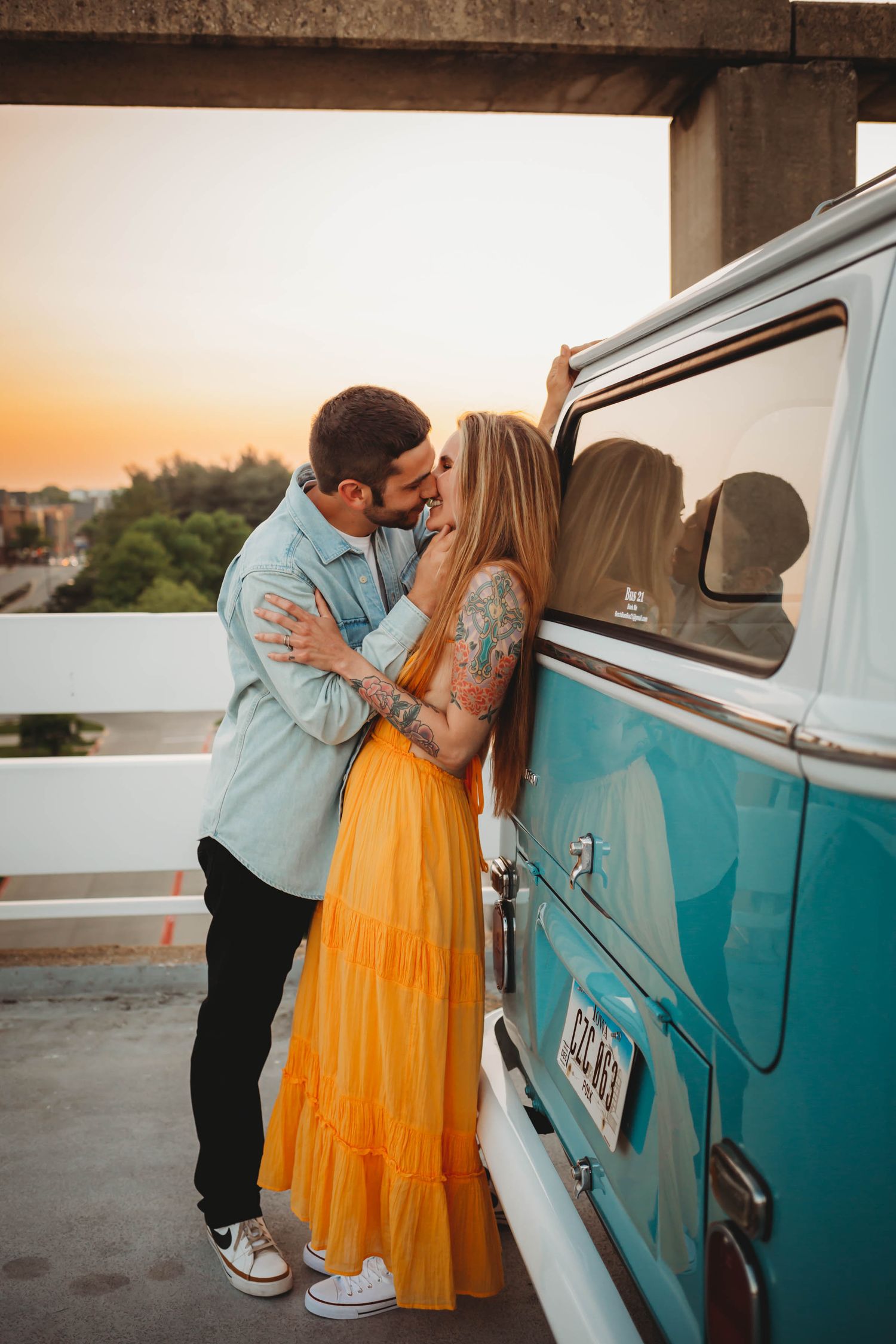 Couple hugs in front of vintage van a Des Moines area parking garage at sunset during a lifestyle family photo session.