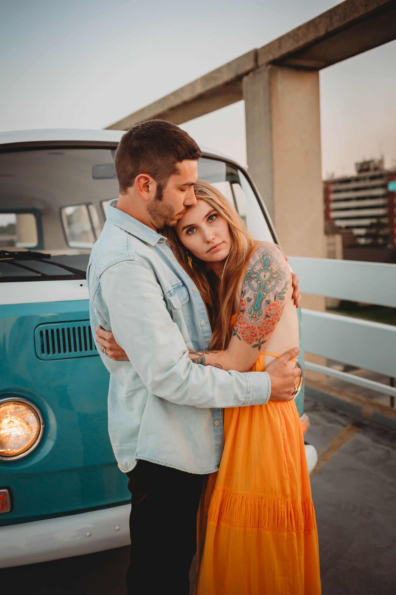 Couple hugs in front of vintage van a Des Moines area parking garage at sunset during a lifestyle family photo session.