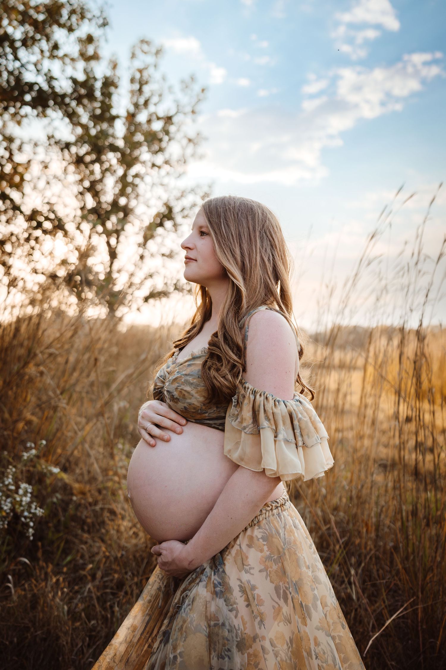 Pregnant woman in a Des Moines area field at sunset during lifestyle maternity photo session.