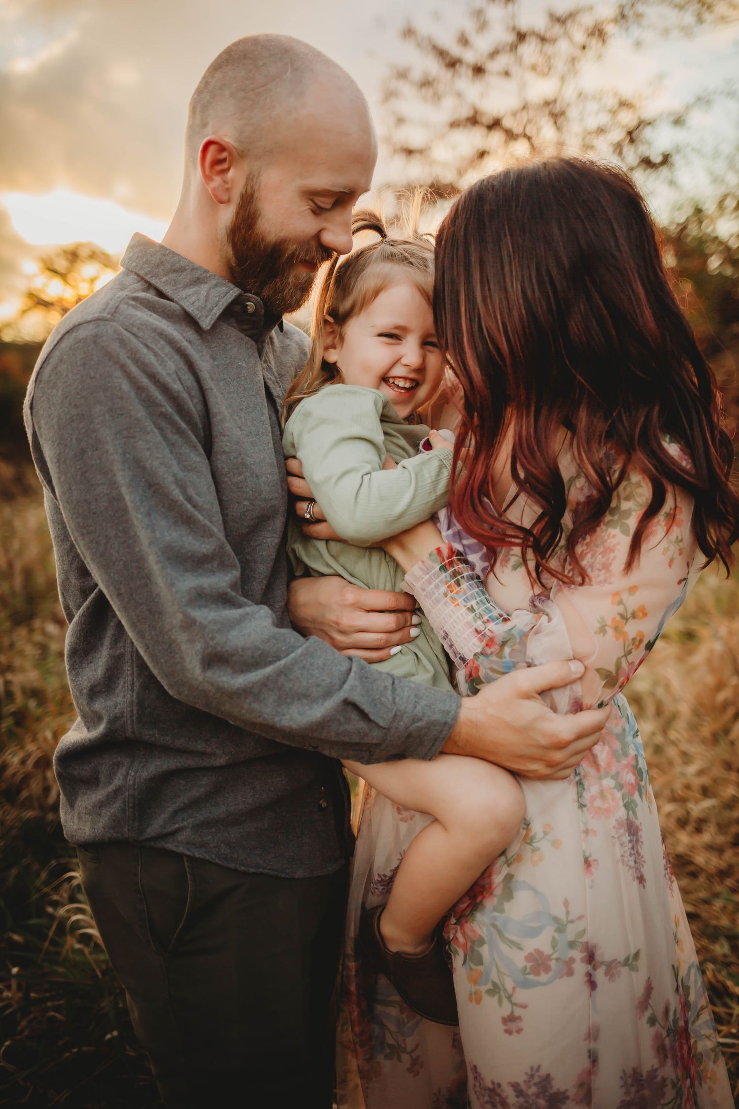 Family embraces in a Des Moines area park at sunset during a lifestyle family photo session.