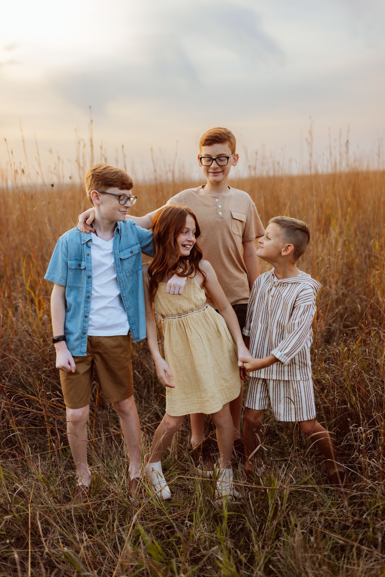 Siblings play in a field in a Des Moines area park at sunset during a lifestyle family photo session.