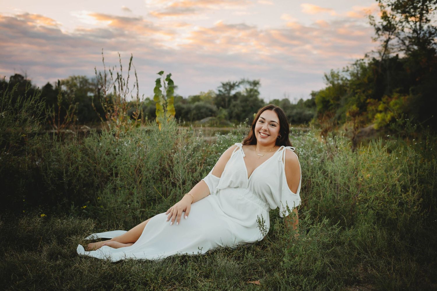 High school senior girl poses in a field in a Des Moines area park during a lifestyle senior photo session.