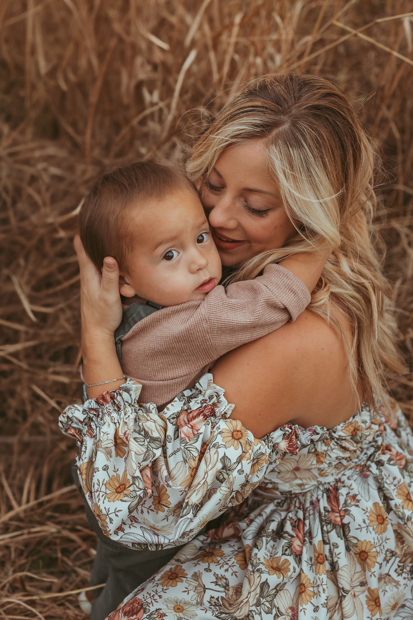 Mother embraces young boy in a Des Moines area park at sunset during a lifestyle family photo session.