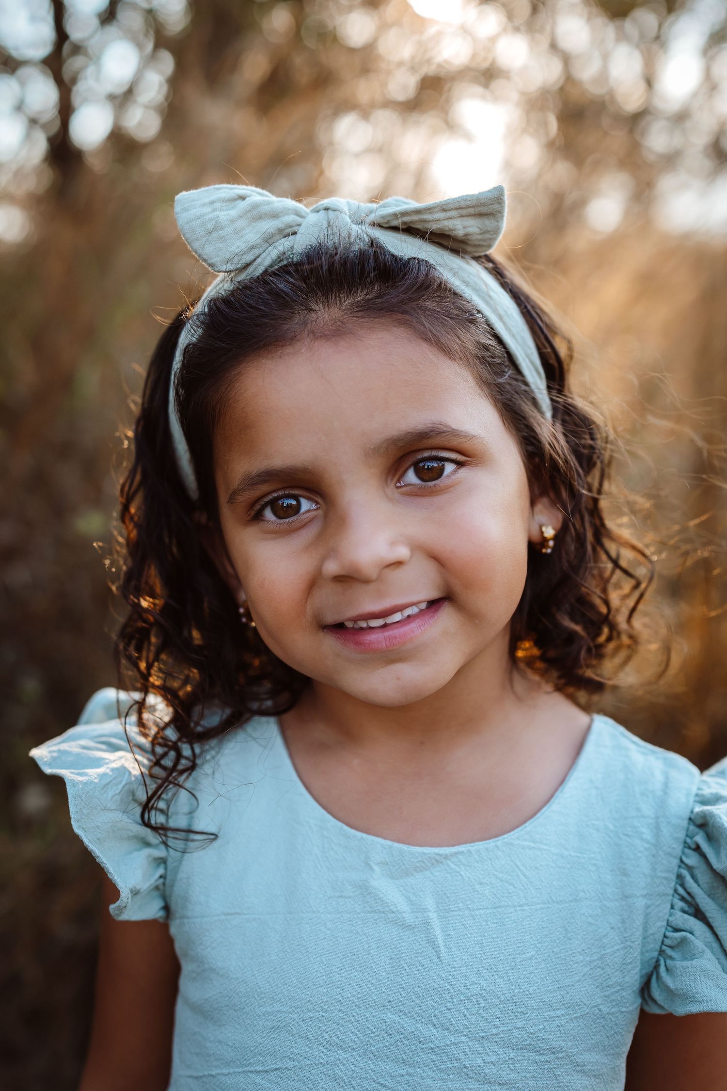 Young girl smiles at camera in a Des Moines area park during a lifestyle family child milestone photo session.