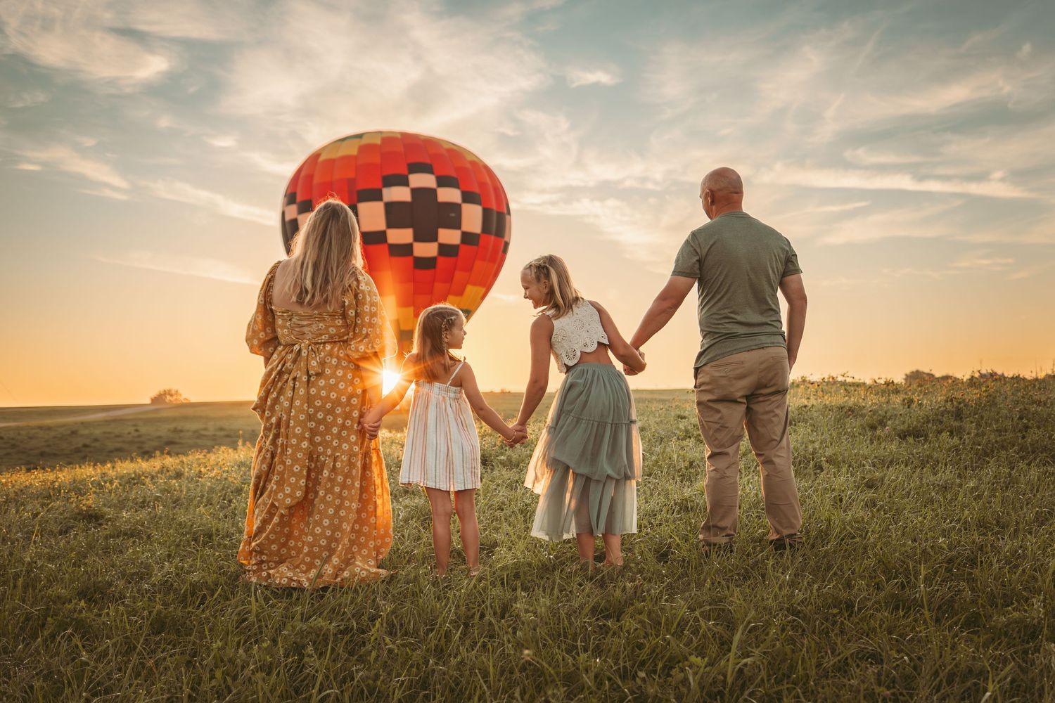 Family watches a hot air balloon at sunrise in a Des Moines area field during a lifestyle family photo session.