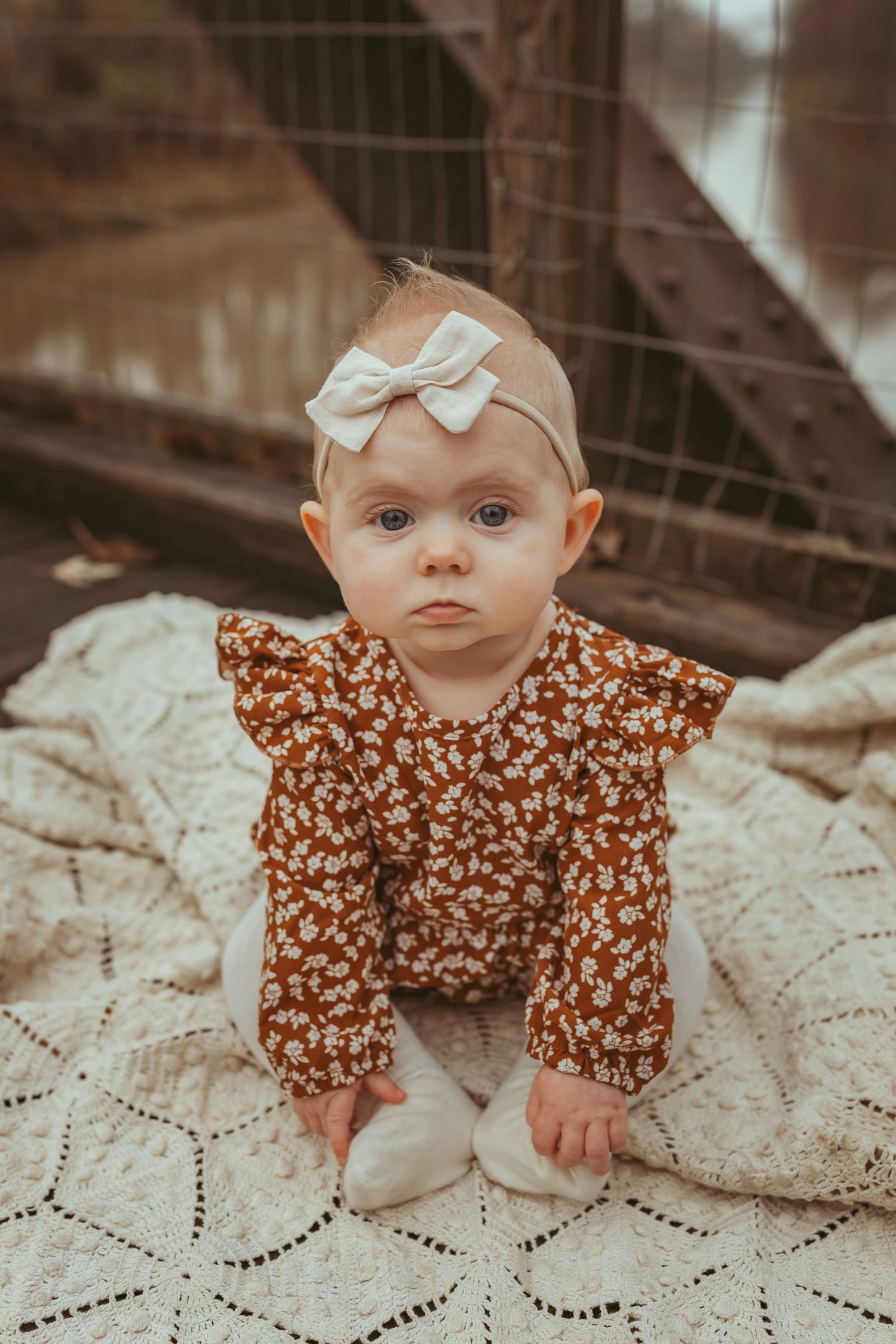 Baby girl sits on vintage blanket in a Des Moines area park during a lifestyle child milestone photo session.