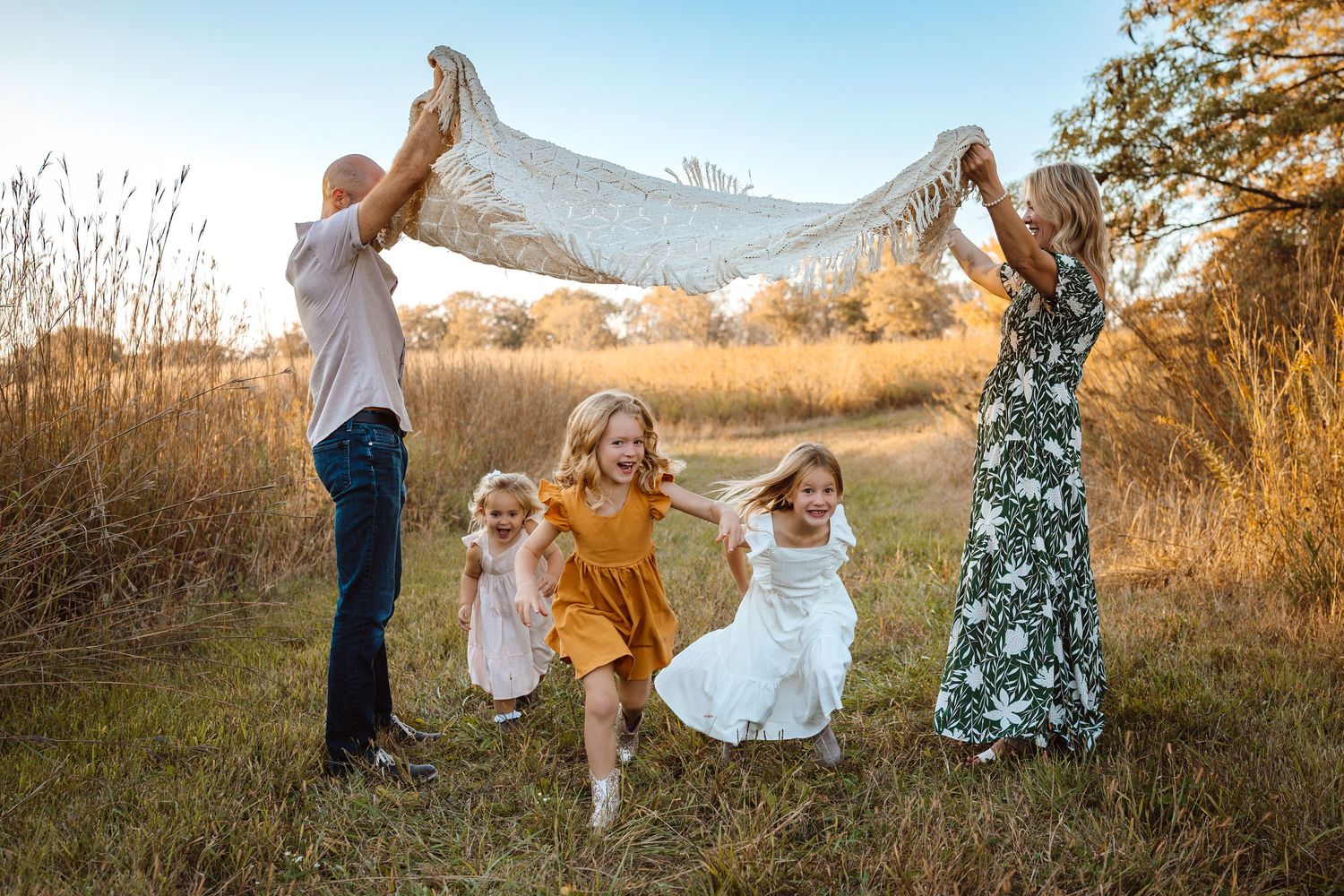 Family plays as in a Des Moines area park at sunset during a lifestyle family photo session.