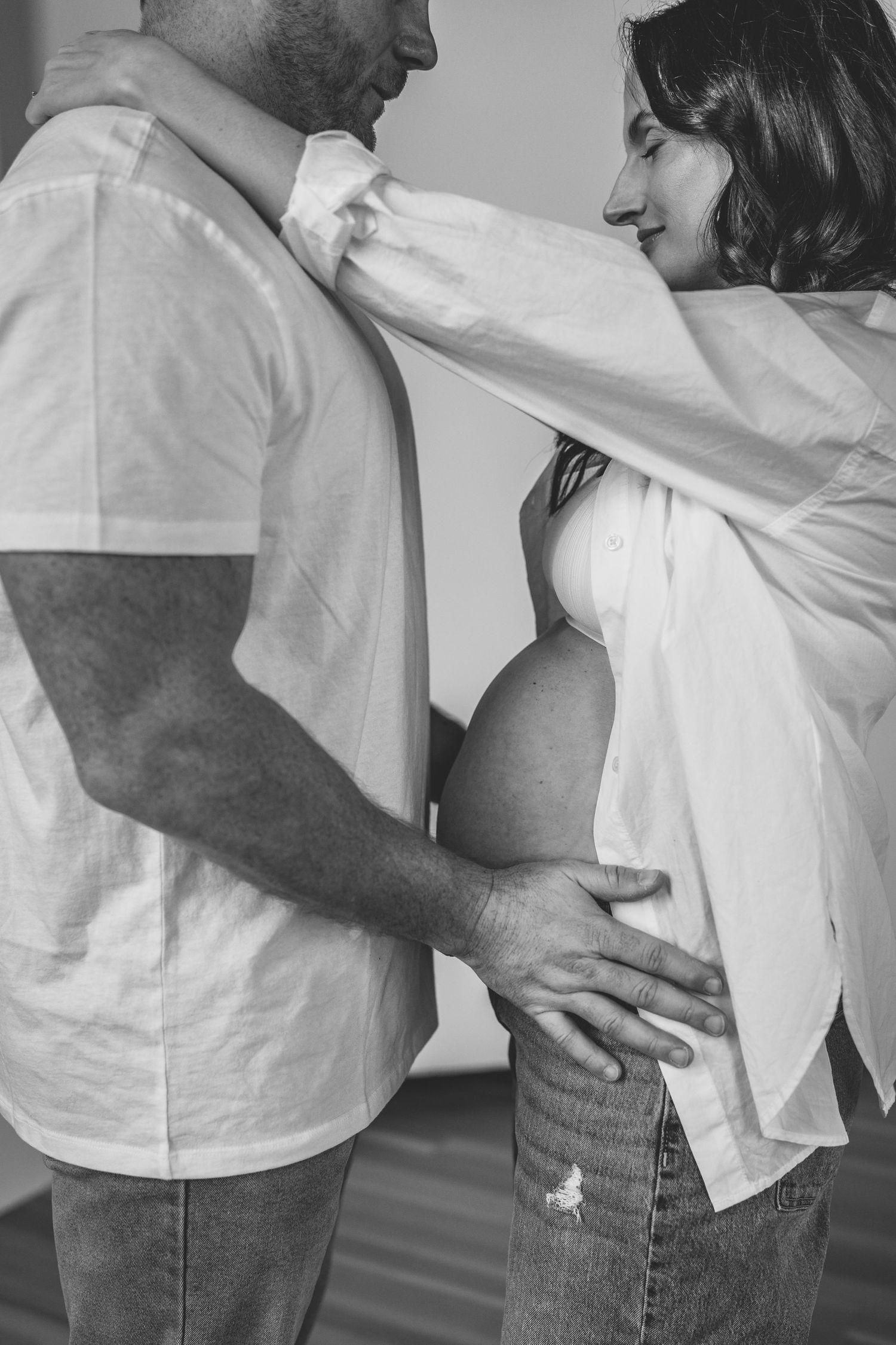 Pregnant woman and partner in a Des Moines studio during lifestyle maternity photo session, shot in black and white.