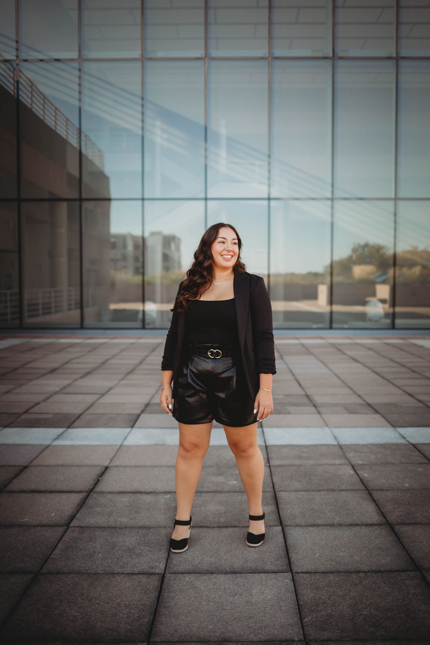 High school senior girl poses in front of a modern building in a Des Moines during a lifestyle senior photo session.