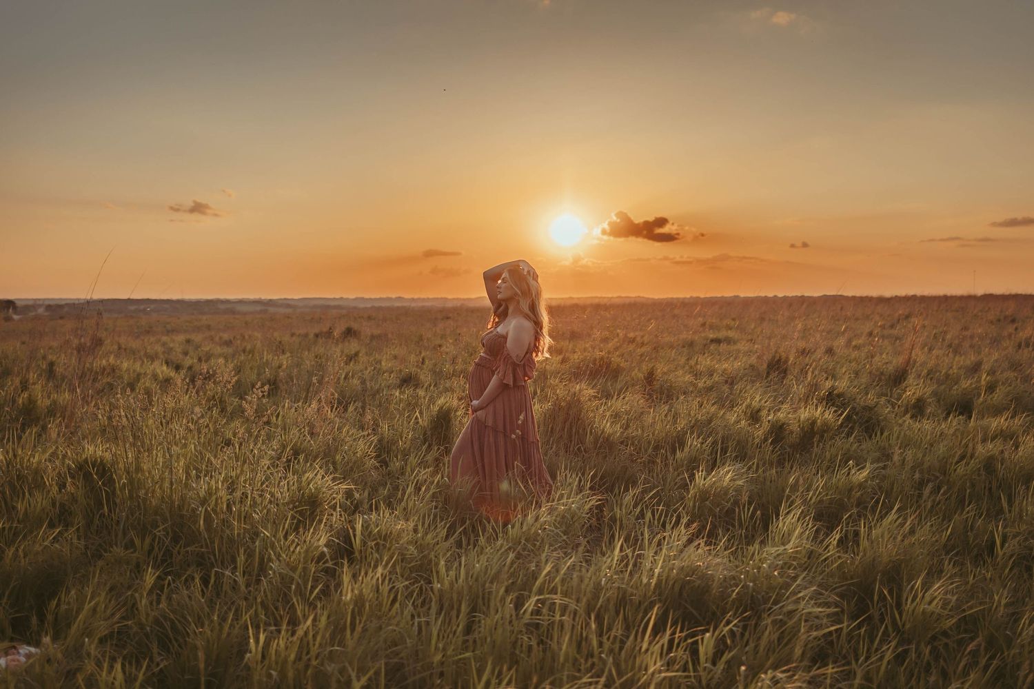 Pregnant woman in a Des Moines area field at sunset during lifestyle maternity photo session.