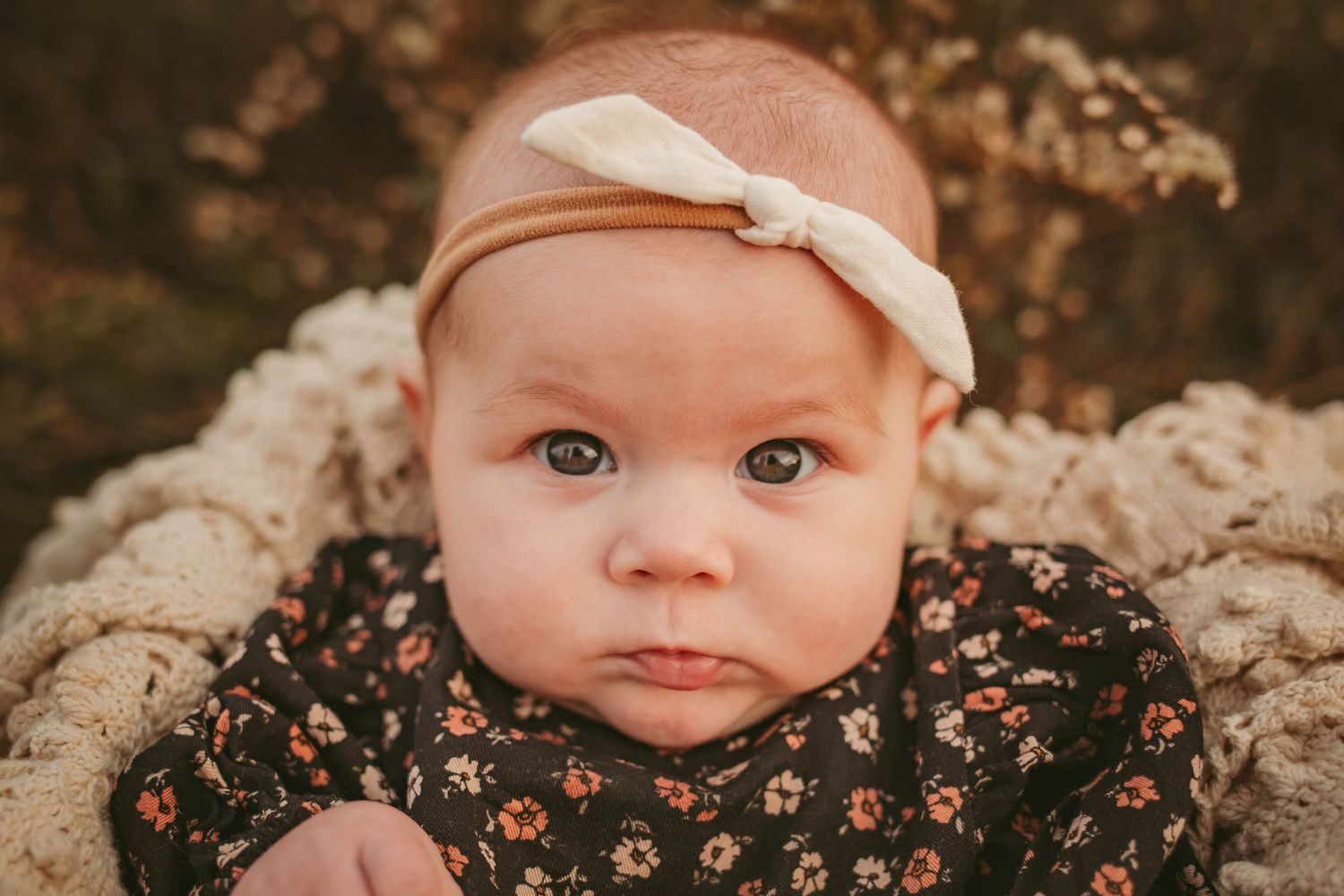 Baby girl looks at camera in a Des Moines area park at sunset during a lifestyle family child milestone photo session.