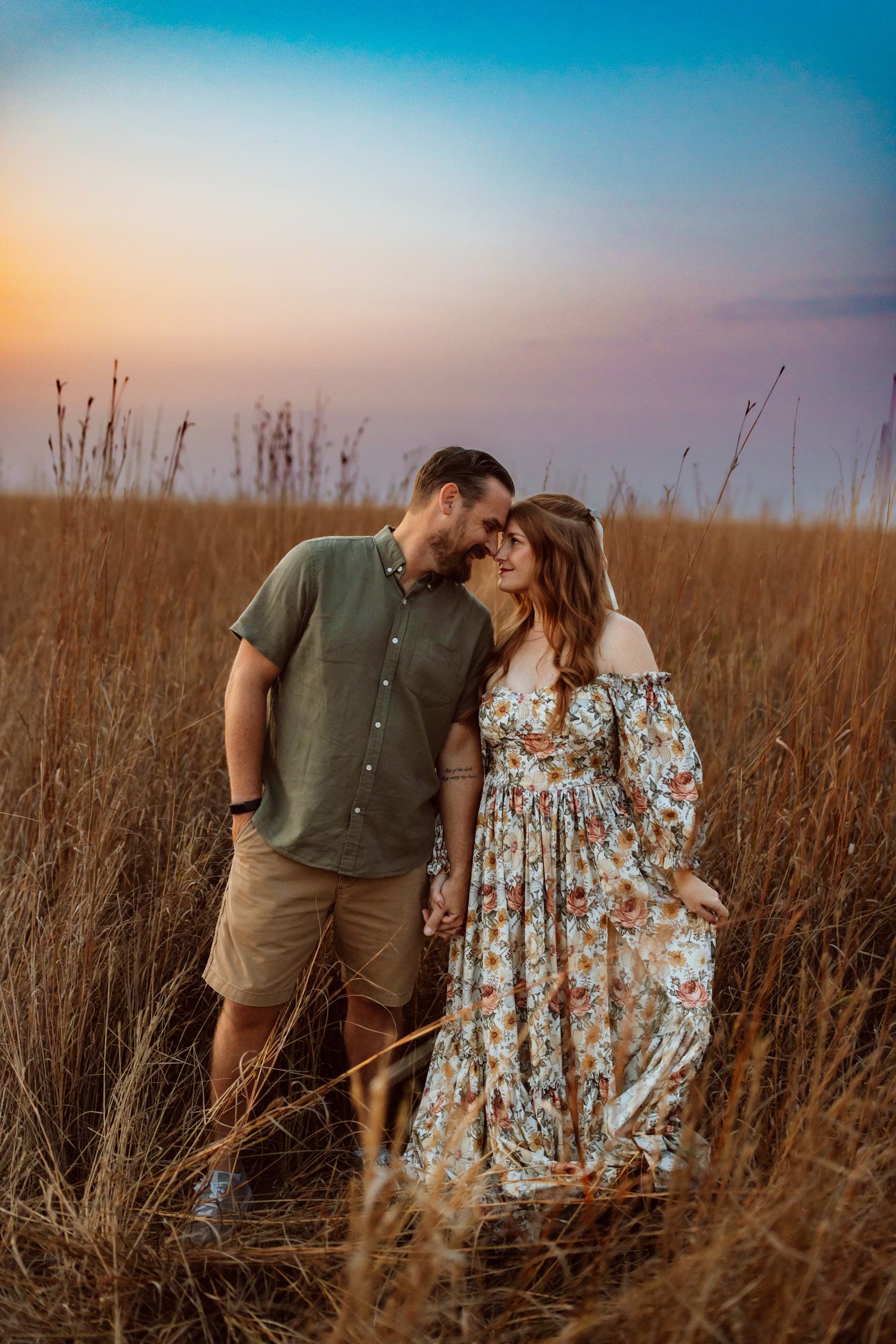 Couple embraces in a field in a Des Moines area park at sunset during a lifestyle family photo session.