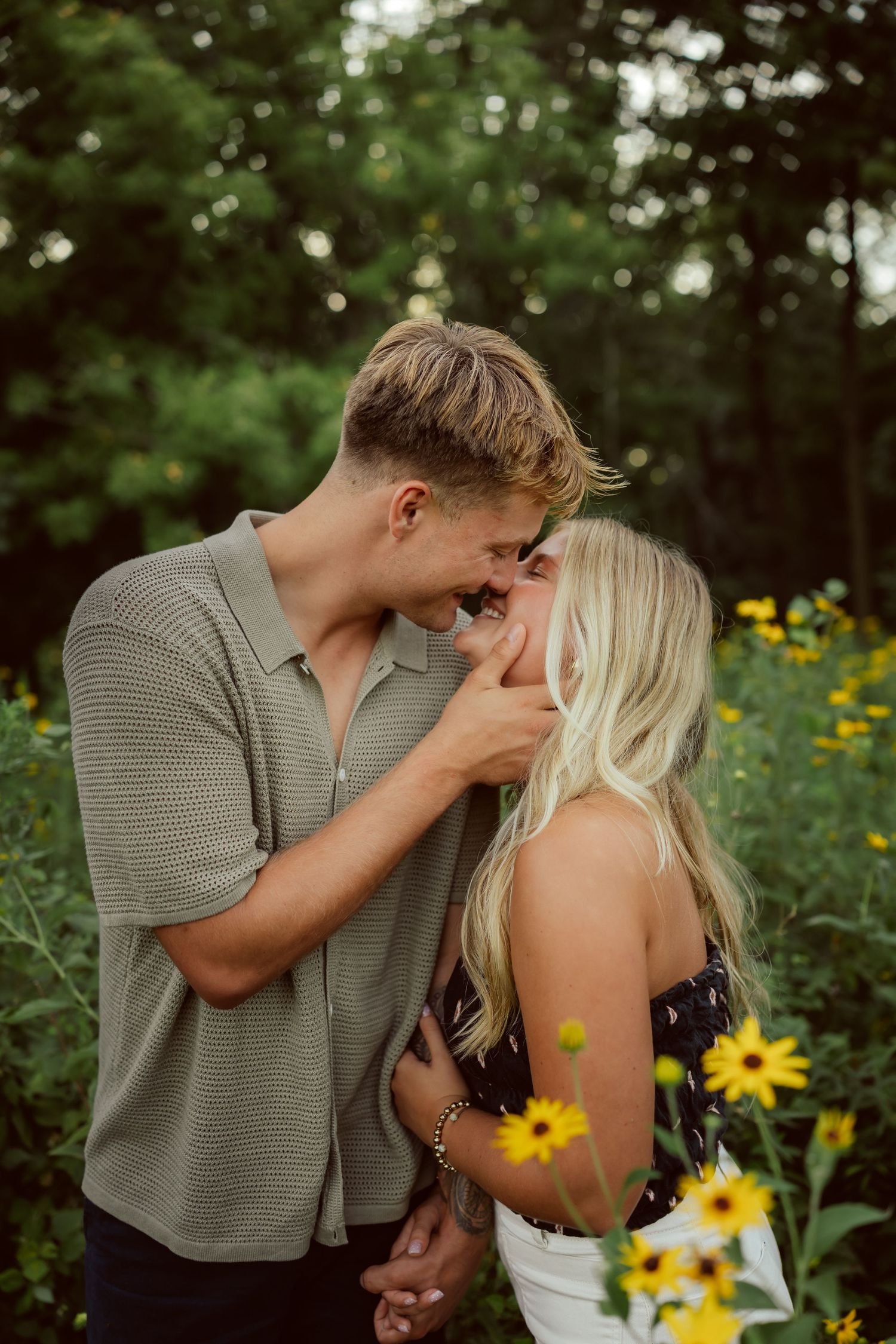 Couple kisses in a field of flowers in a Des Moines area park at sunset during a lifestyle family photo session.