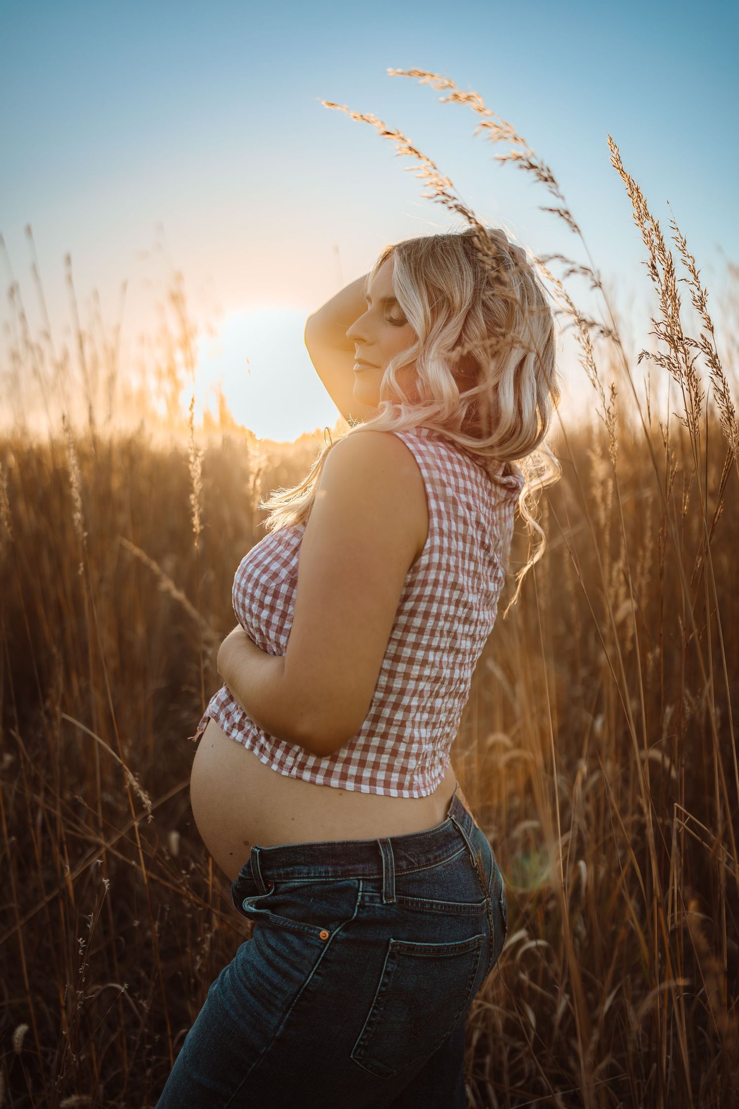 Pregnant woman in a Des Moines area field at sunset during lifestyle maternity photo session.