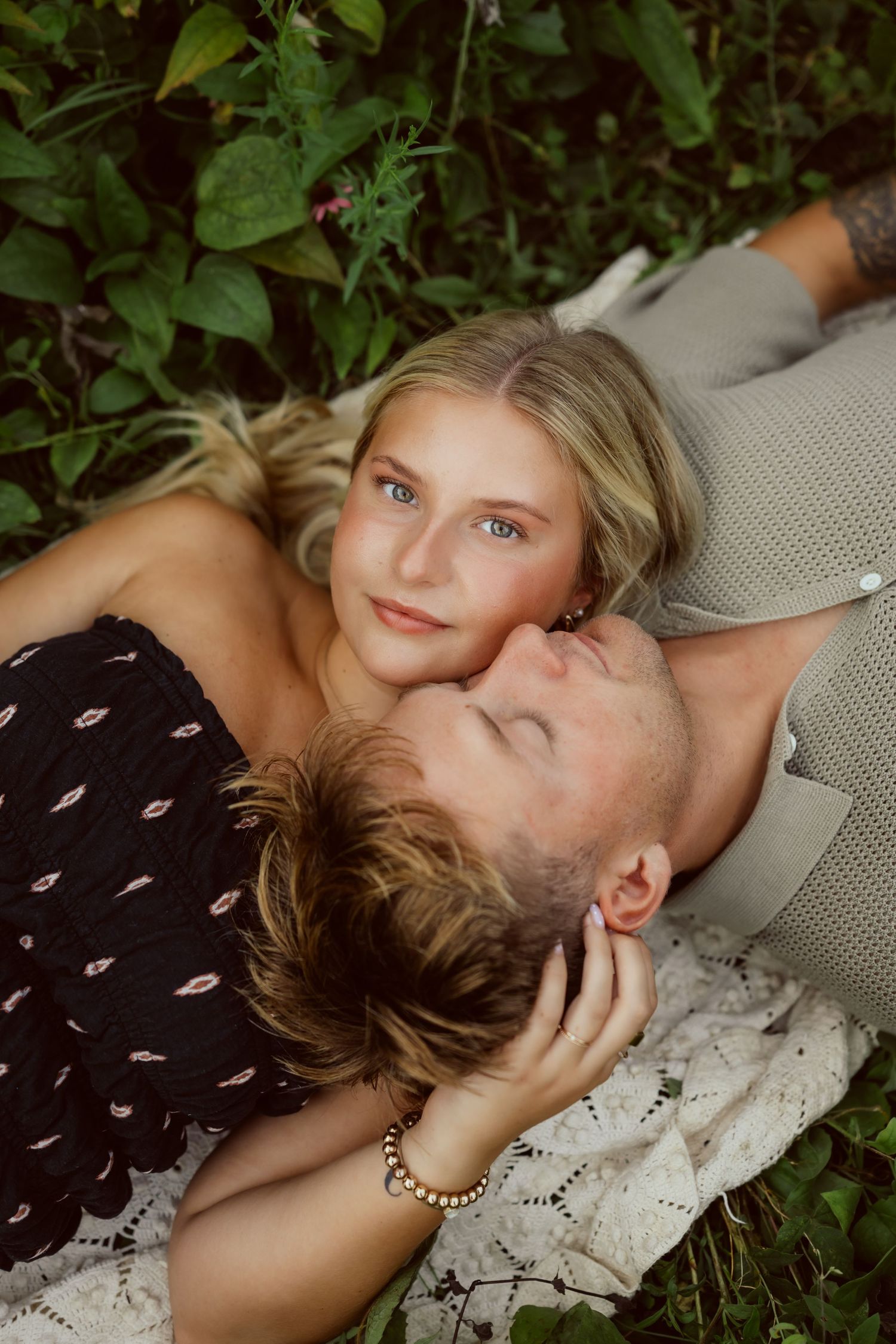 Couple lays in a field of flowers in a Des Moines area park at sunset during a lifestyle family photo session.