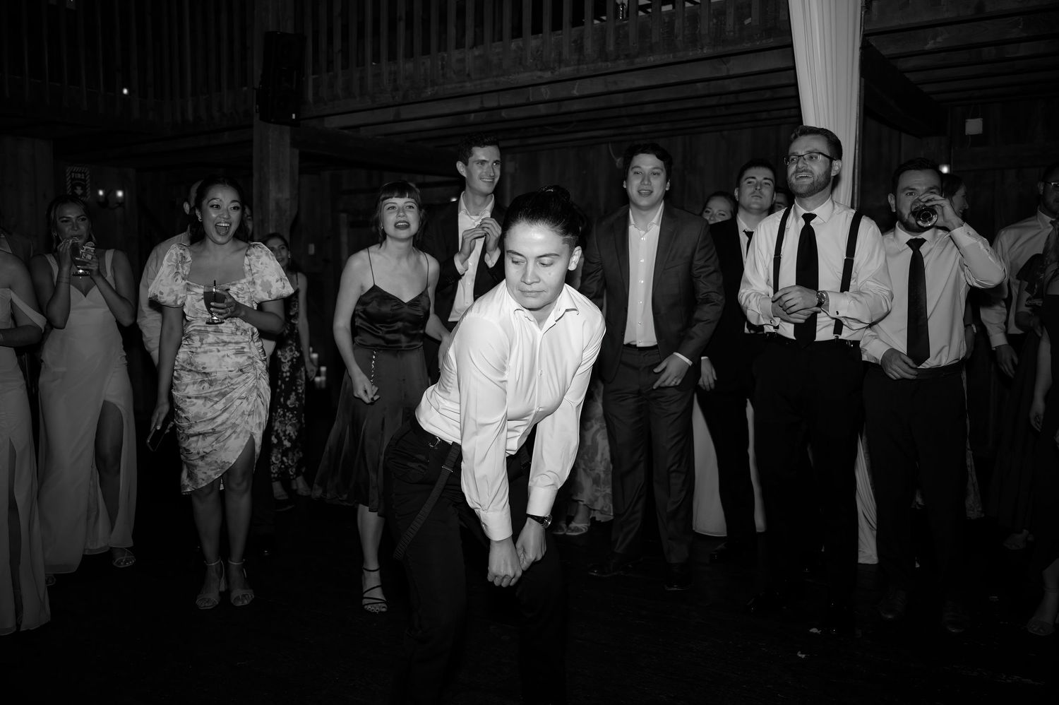Wedding guests dancing energetically on the dance floor at a lively black and white reception party.