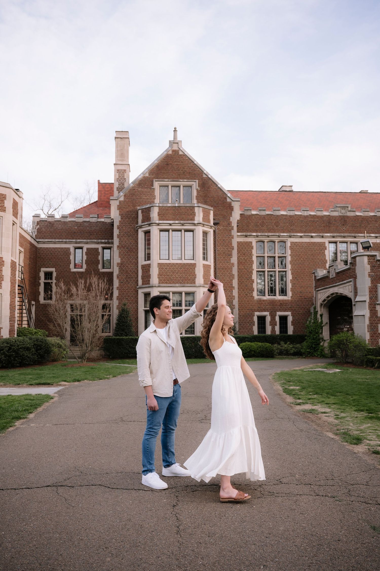 Dancing together in front of historic brick university building during spring.
