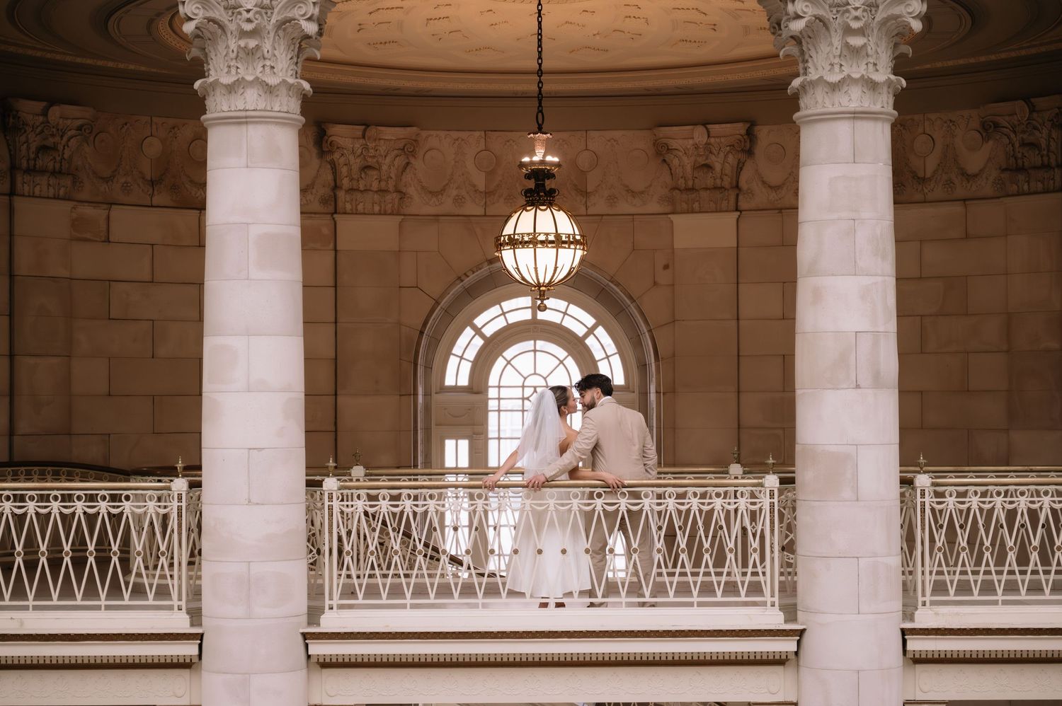 Classical colonnade with white marble pillars and arched ceilings in a grand historic interior space.