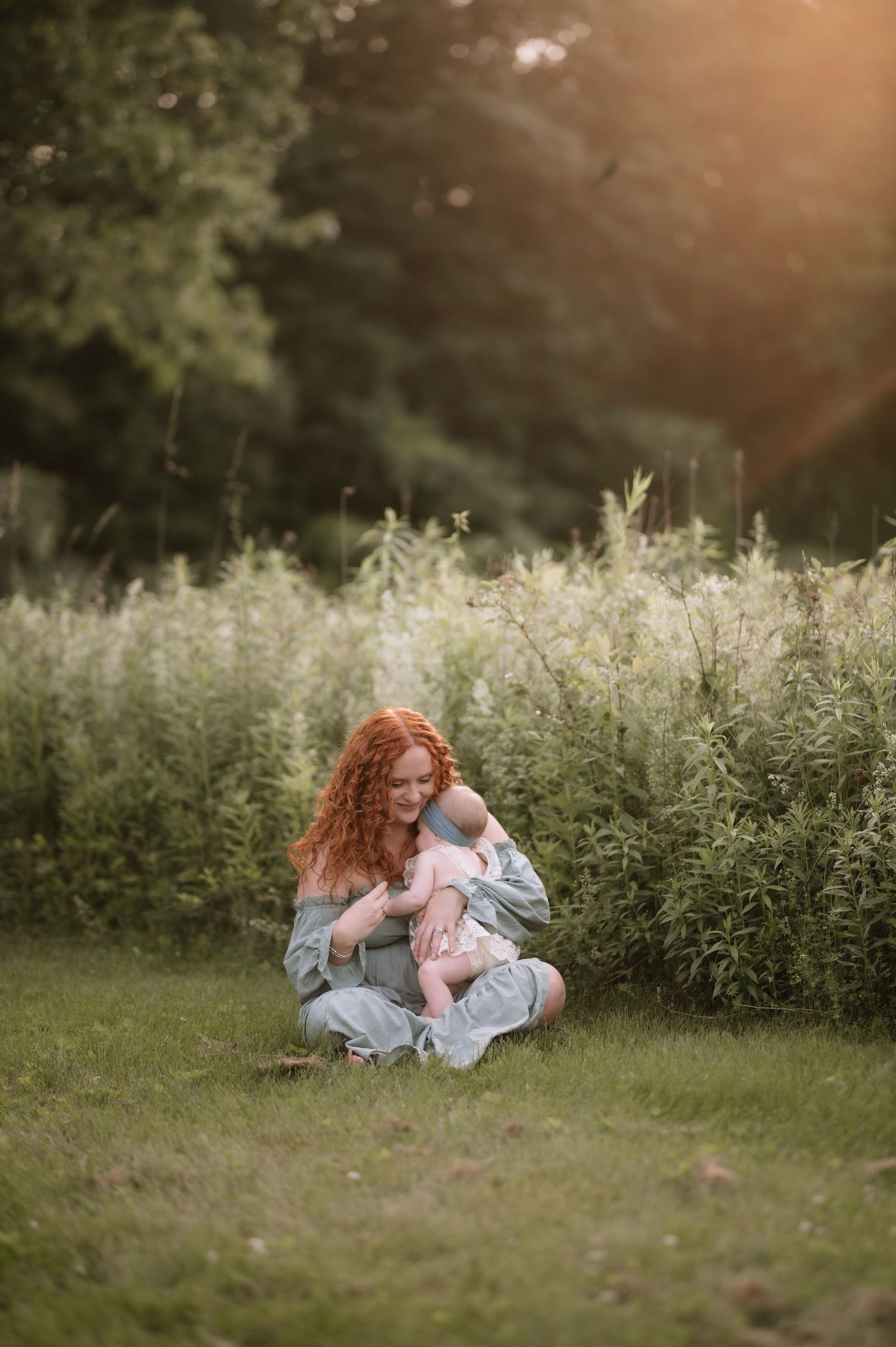 Tender sunset moment in a meadow with tall wildflowers and natural golden light streaming through the greenery.
