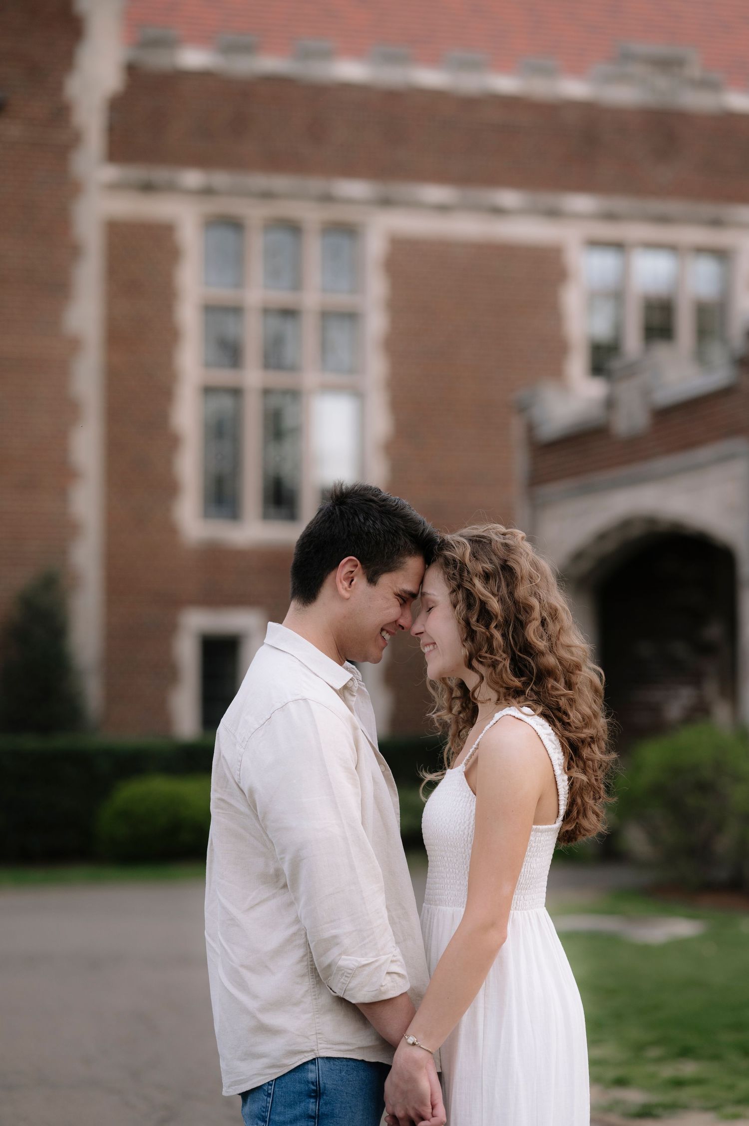 Intimate moment shared between couple outside historic brick building entrance.