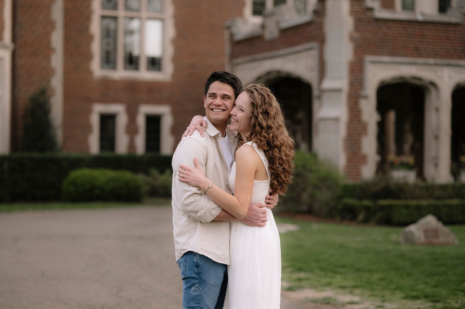 Romantic embrace in front of vintage brick building with Gothic architecture.