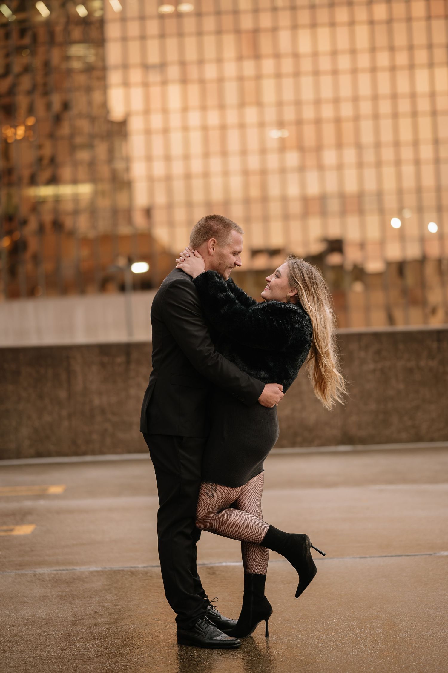 A romantic embrace on a city street at night with glowing lights in the background.
