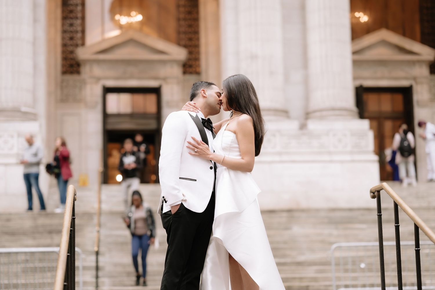 Romantic wedding couple embracing on grand stone steps of historic building.