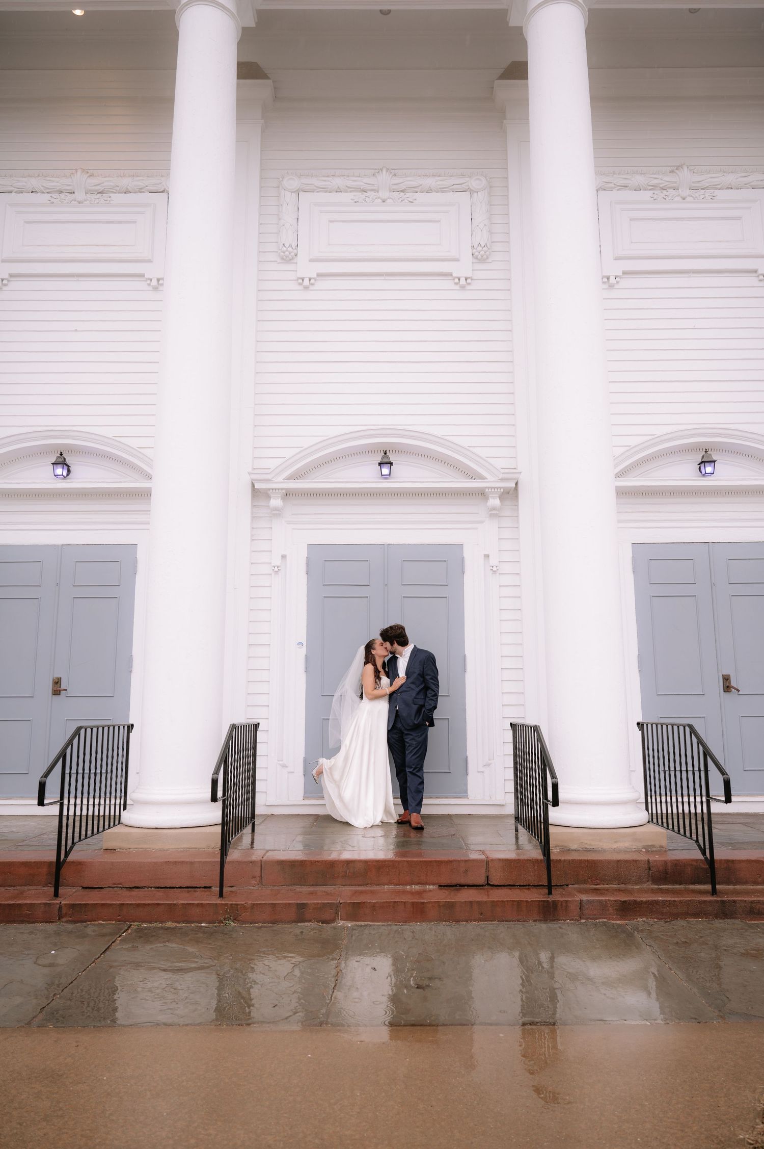 Wedding portrait under grand white columns of classic church architecture.