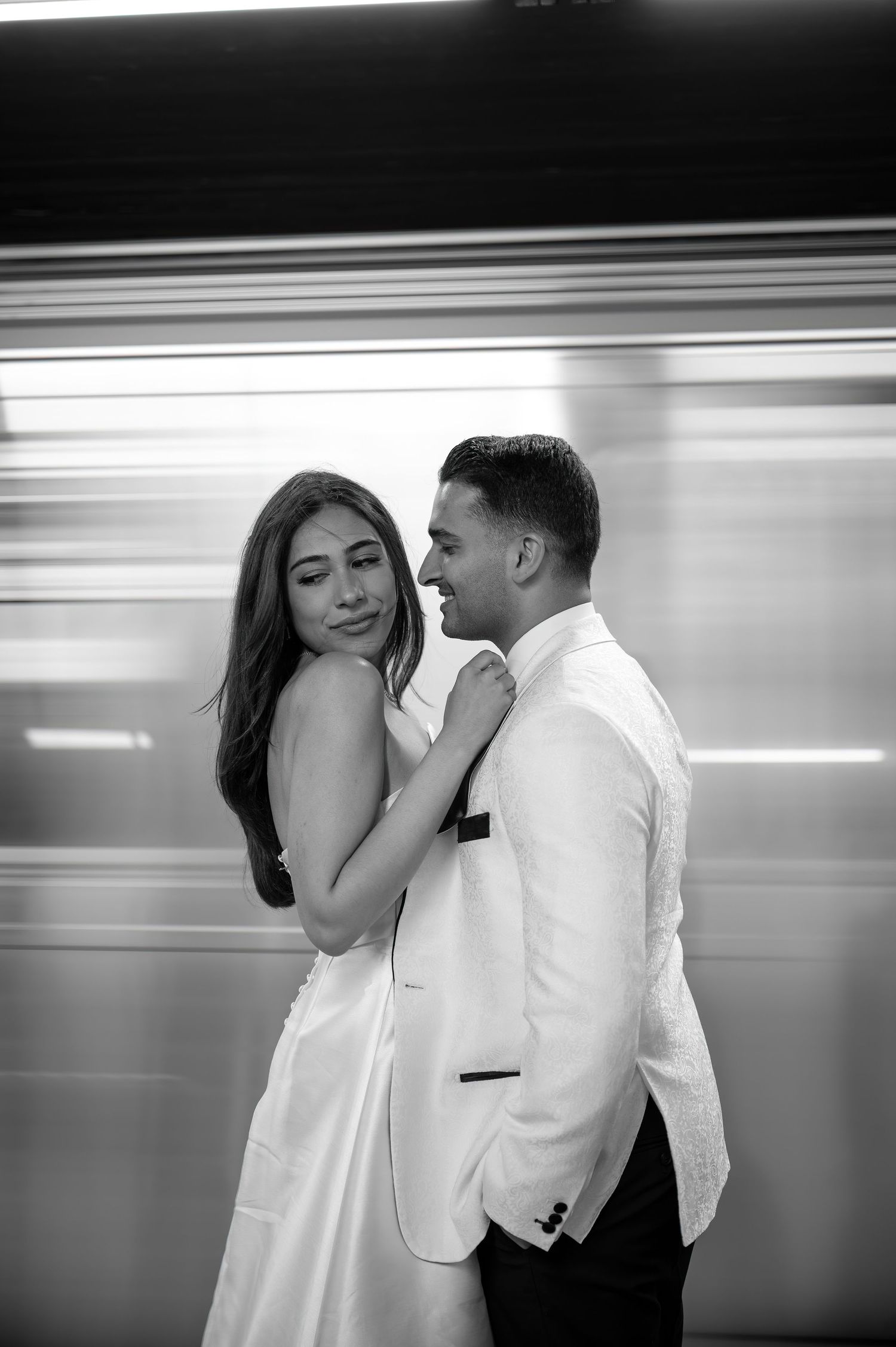 Black and white portrait of newlyweds with motion blur effect in subway station.