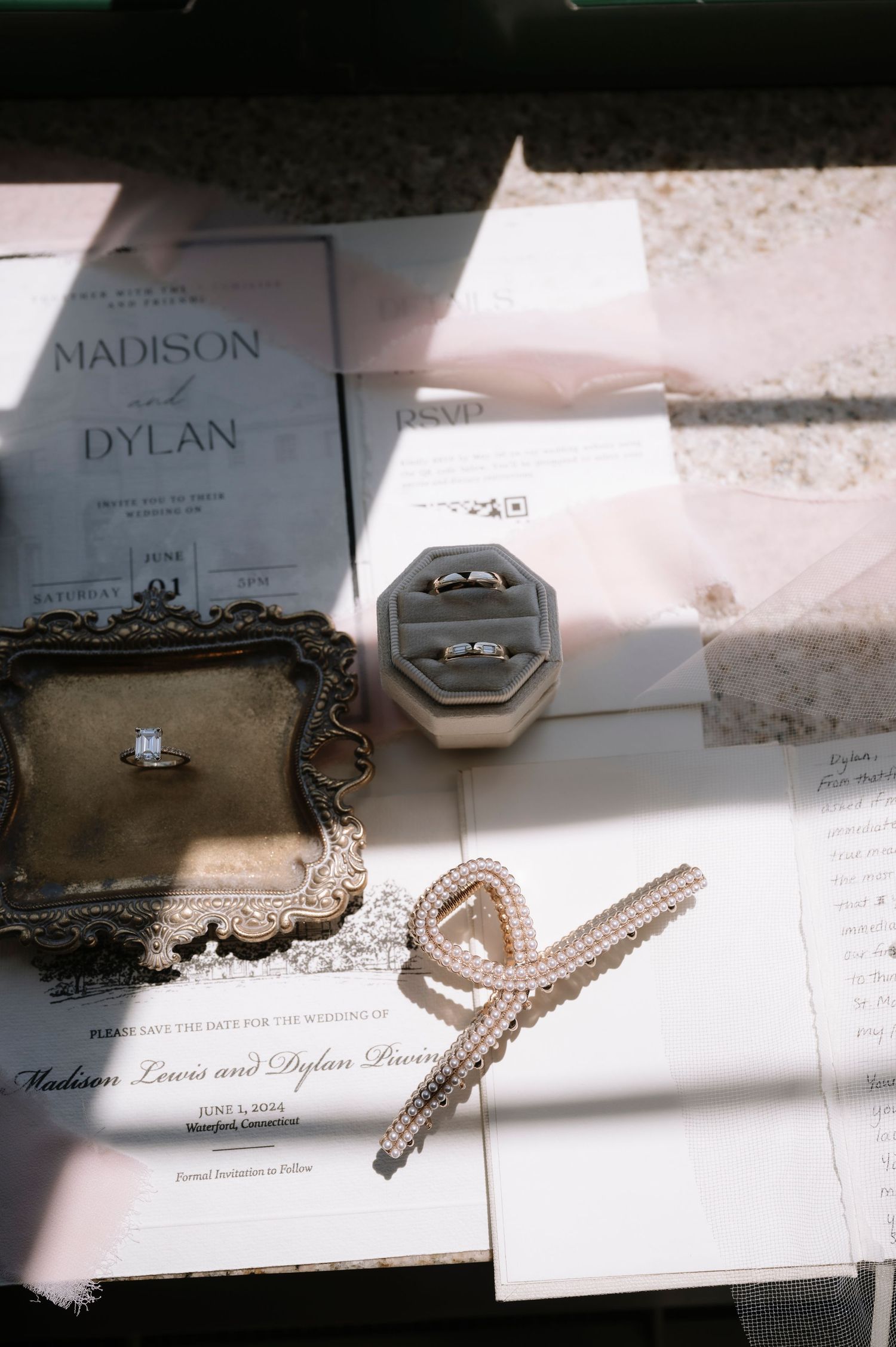 Wedding invitation details with jewelry pieces, including a ring box and accessories in soft natural lighting.